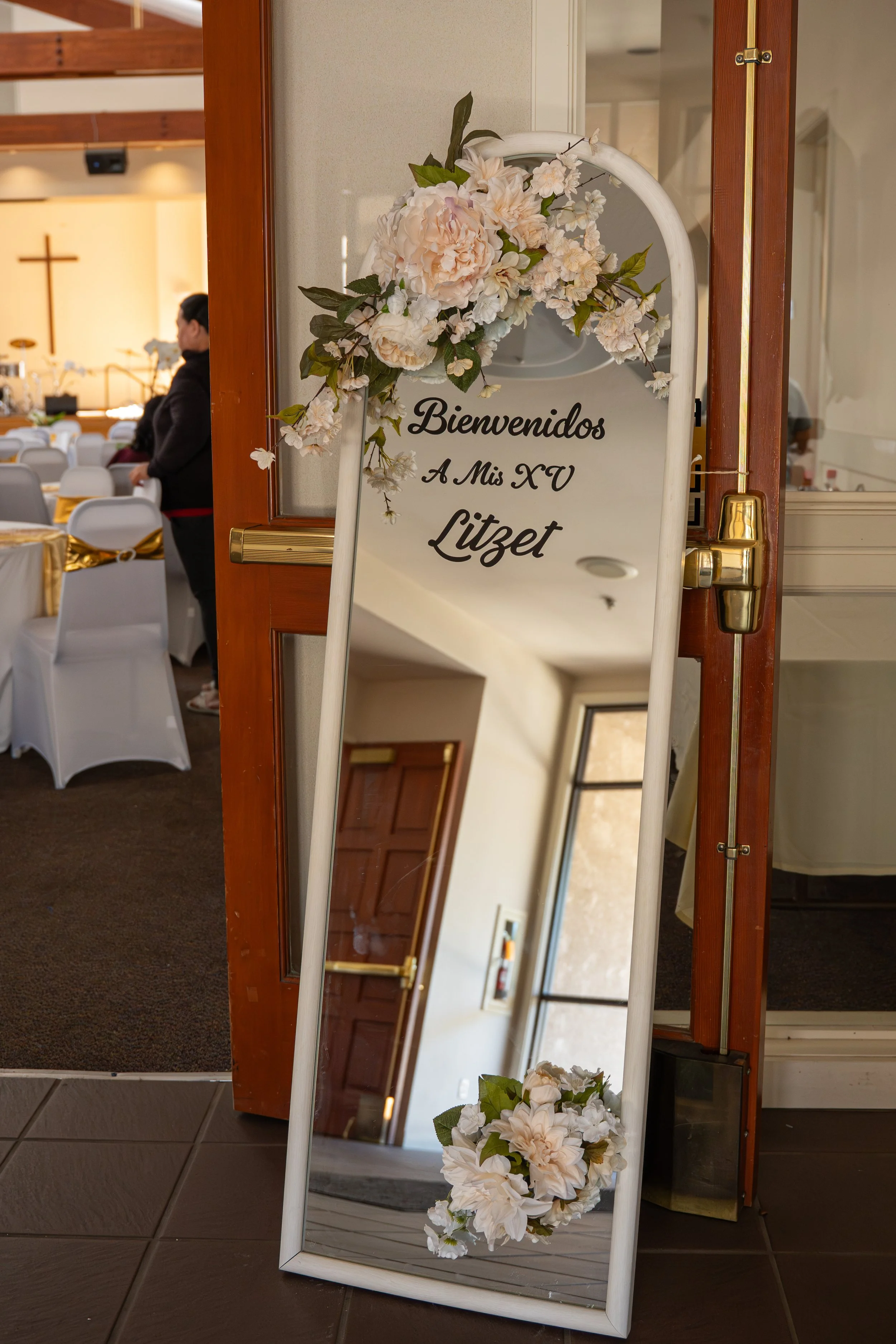 Bouquet of pink roses, calla lilies, white baby's breath, and greenery on a white table.