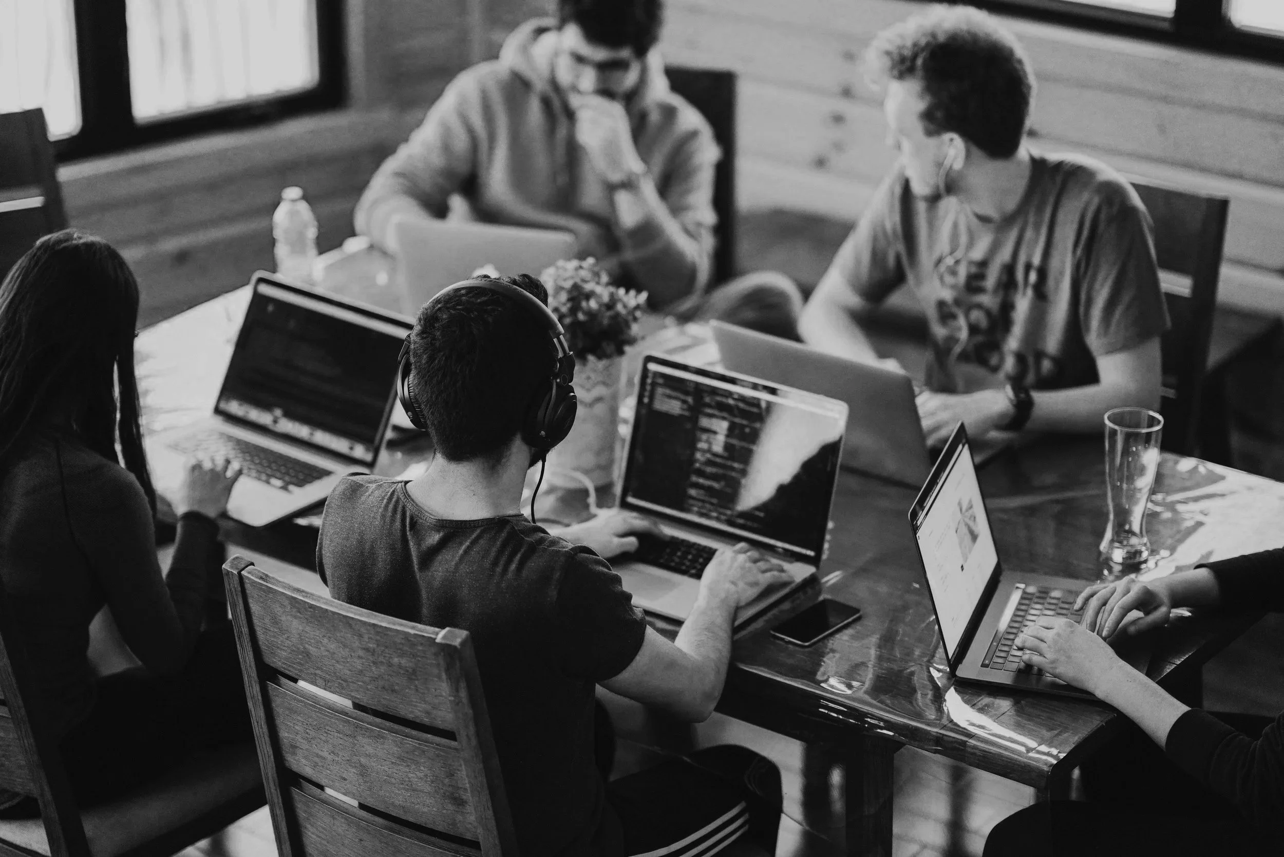 A group of five people working on laptops and computers, talking about modern methods of construction.
