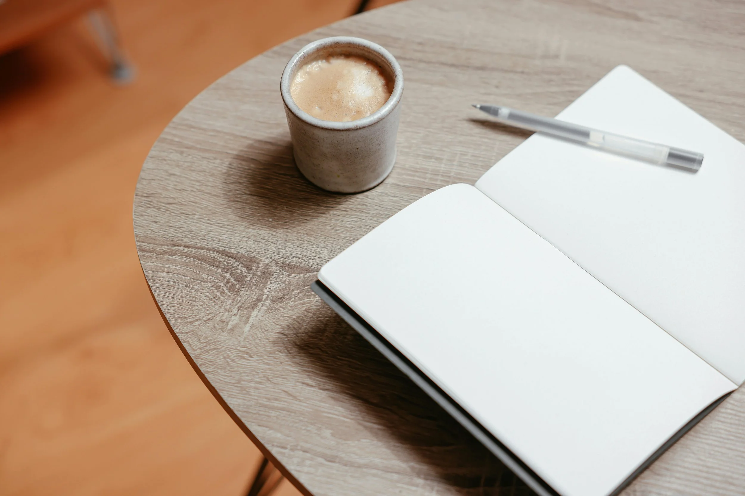 Coffee table with notebook, pen and ceramic mug coffee