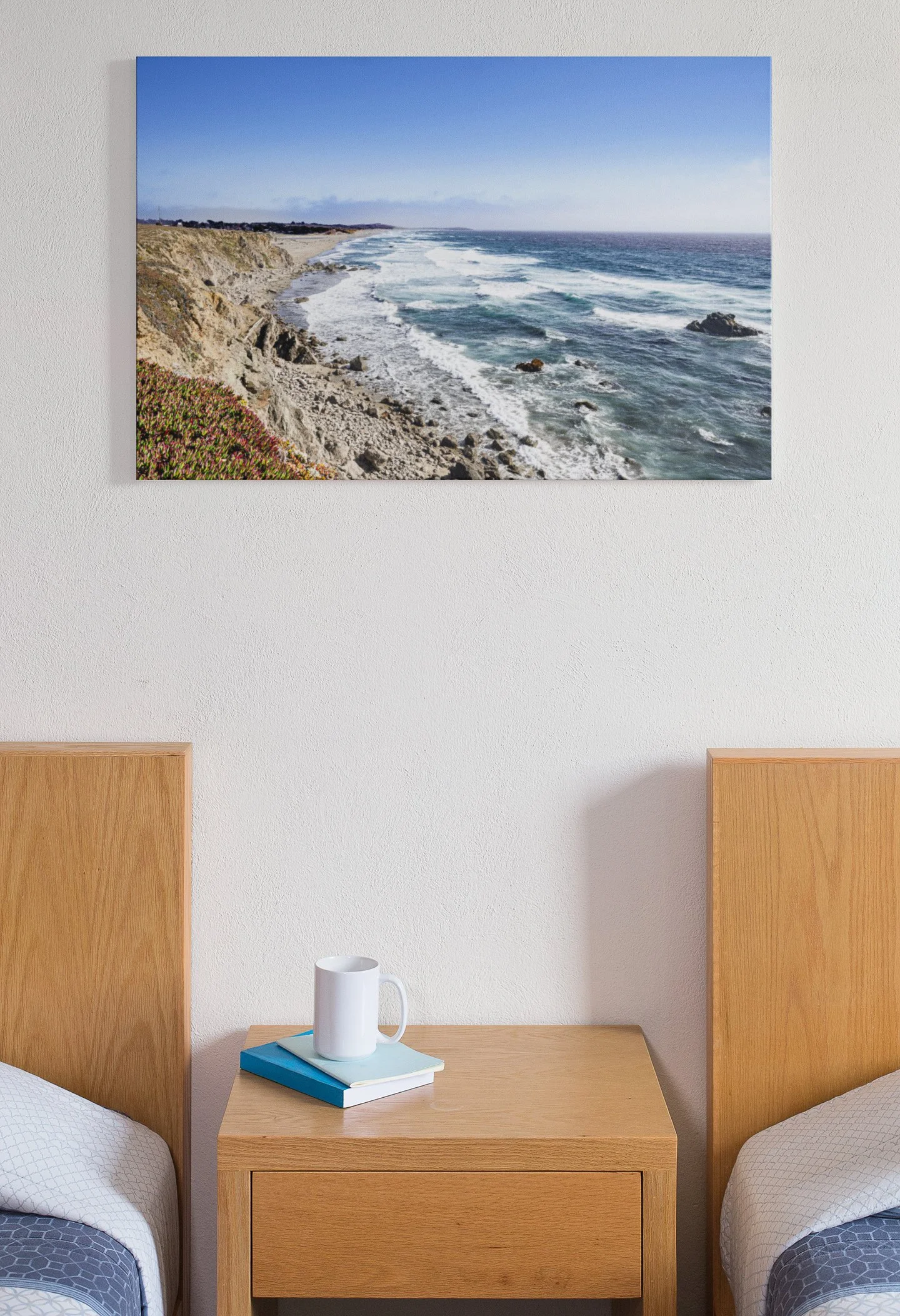 Photograph of a rocky coastline with waves crashing against rocks, taken under a clear blue sky