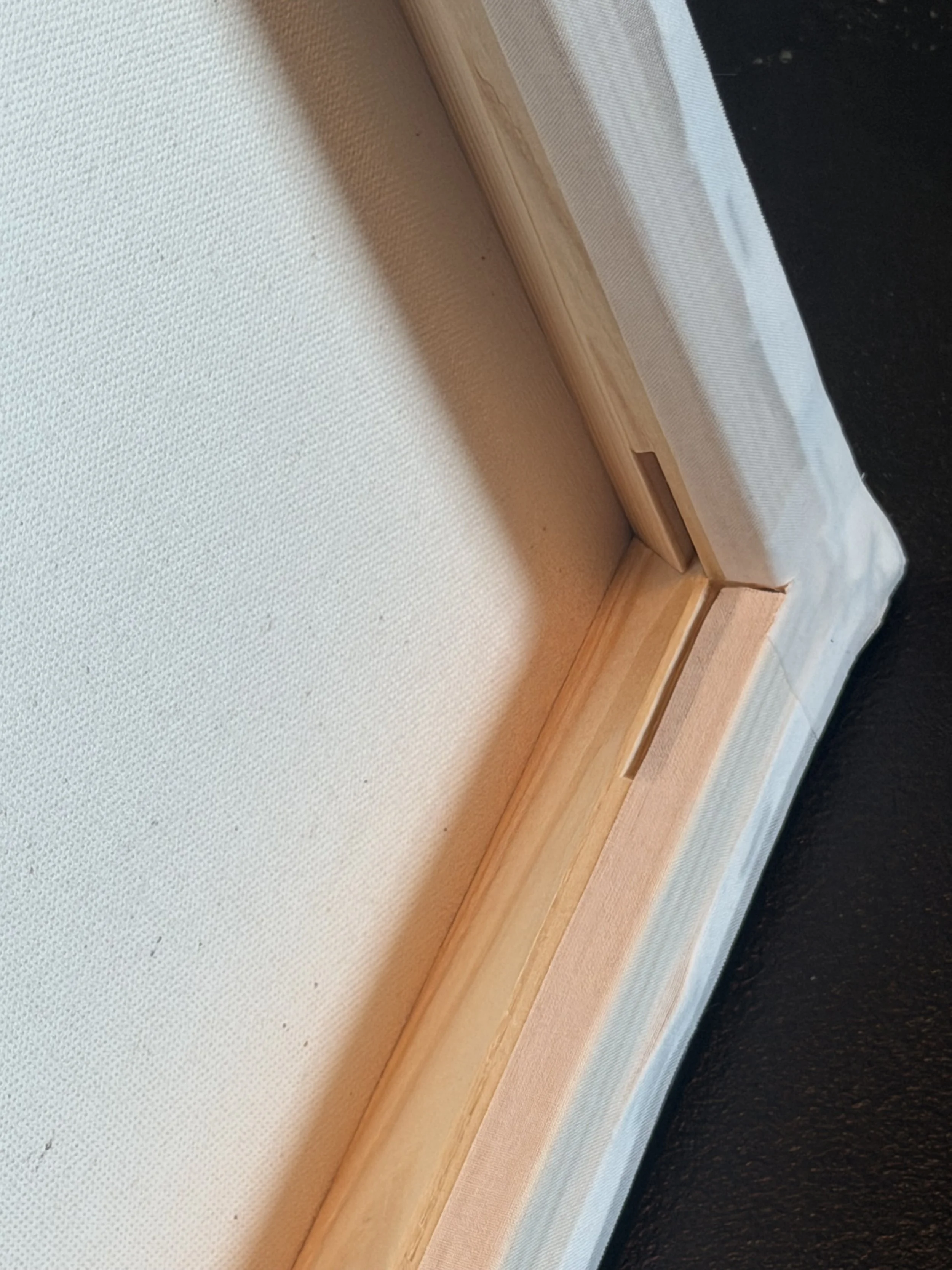 Close-up photo of a wooden frame with a canvas stretched over it, viewed from an angle.