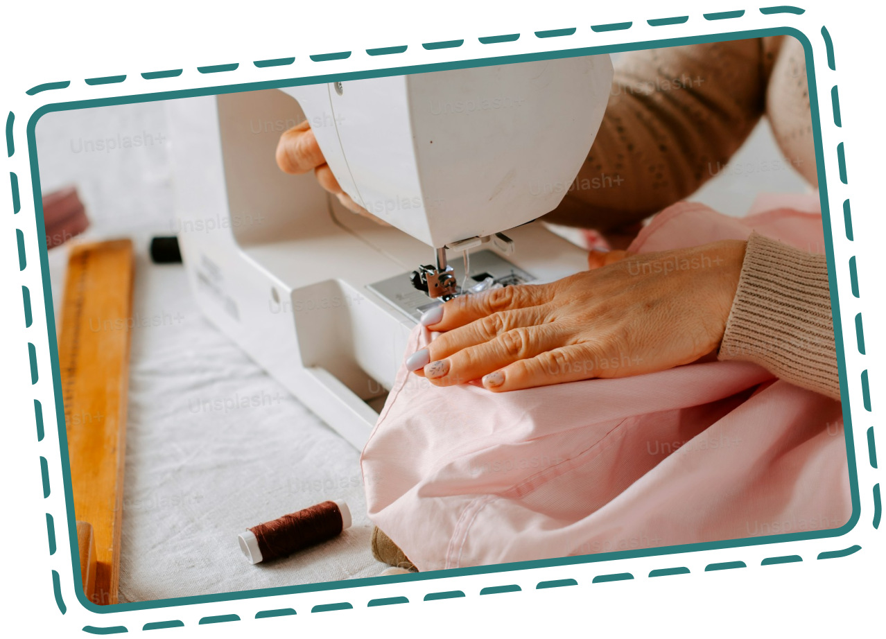 Person sewing pink fabric on a sewing machine, with sewing tools nearby.