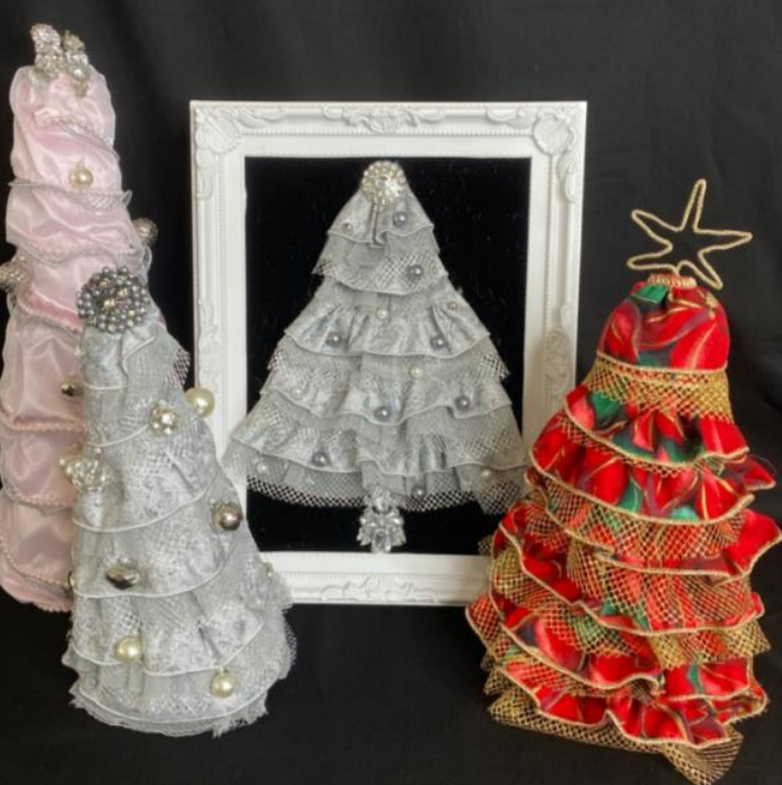 Decorative Christmas trees and a framed mirror on a black background, including a pink, silver, white, and red tree with ornaments and ribbons.