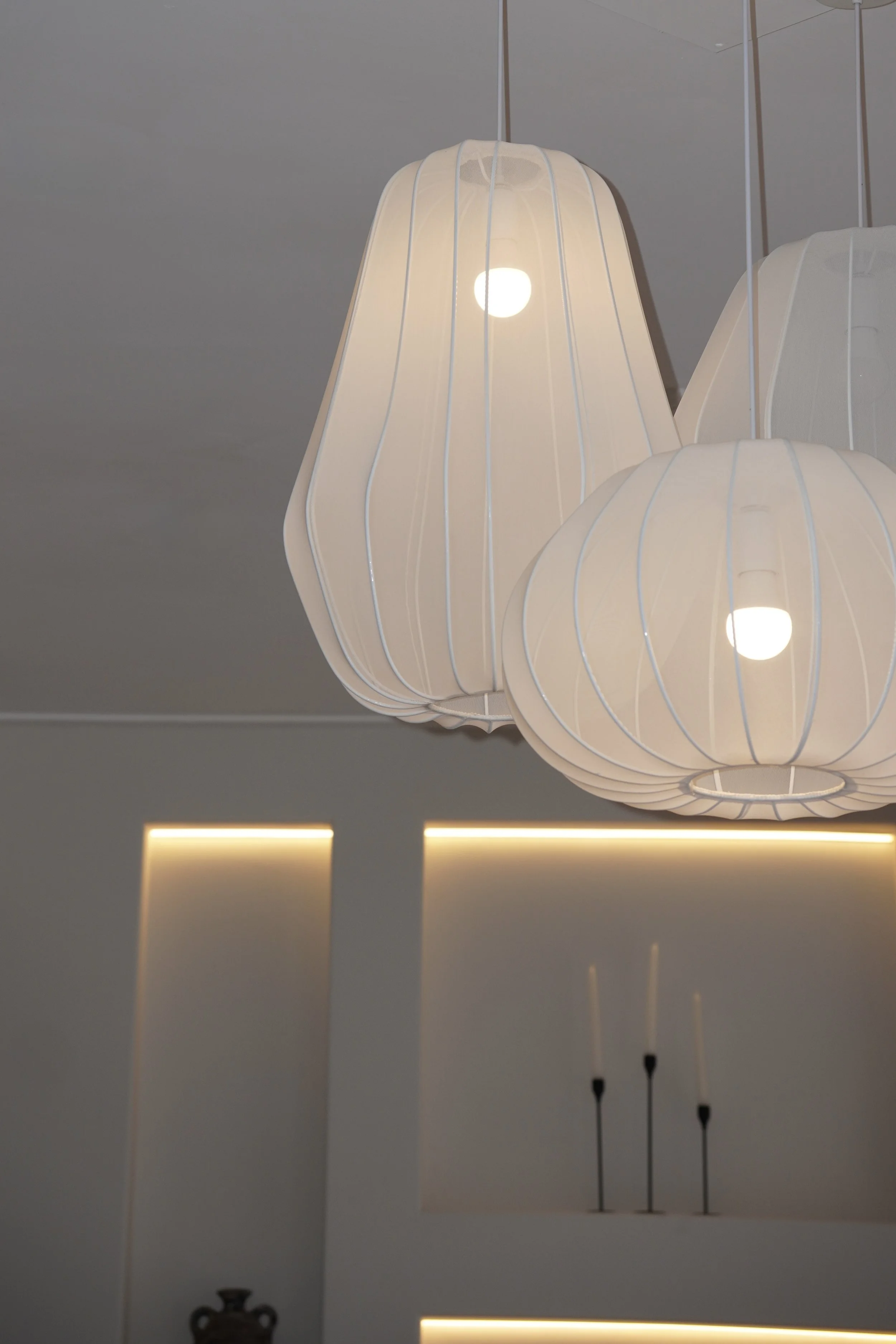 White pendant light fixture with vertical blue stripes hanging from a white ceiling. Minimalistic interior design with ambient lighting.