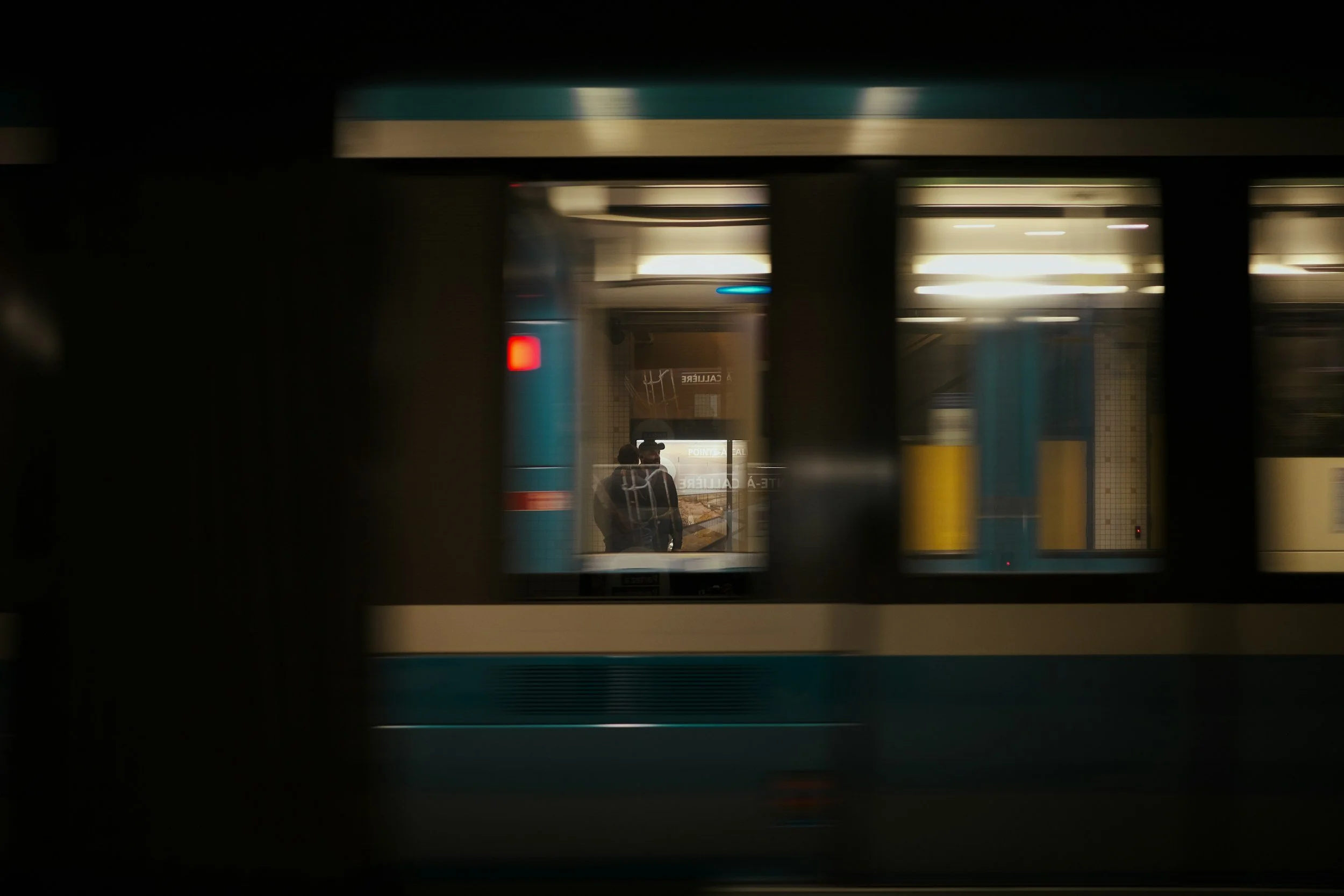 People standing in a subway station reflected in train window