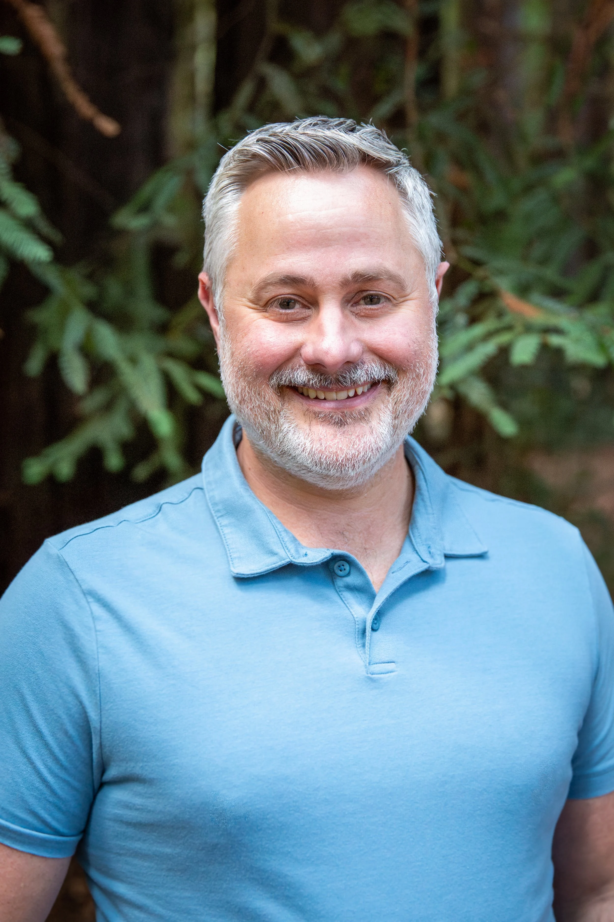 Matthew Cobb smiling outdoors in a blue polo shirt.