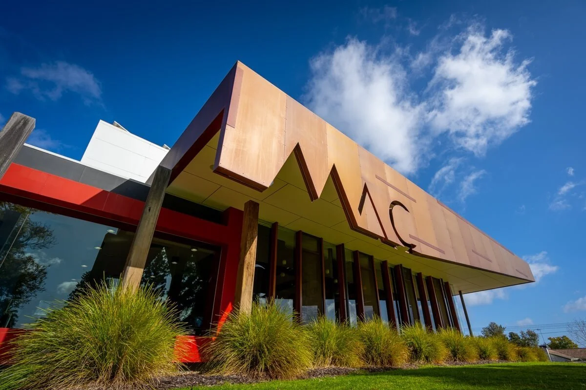 A person placing a pizza into a wood-fired oven with a visible flame inside.