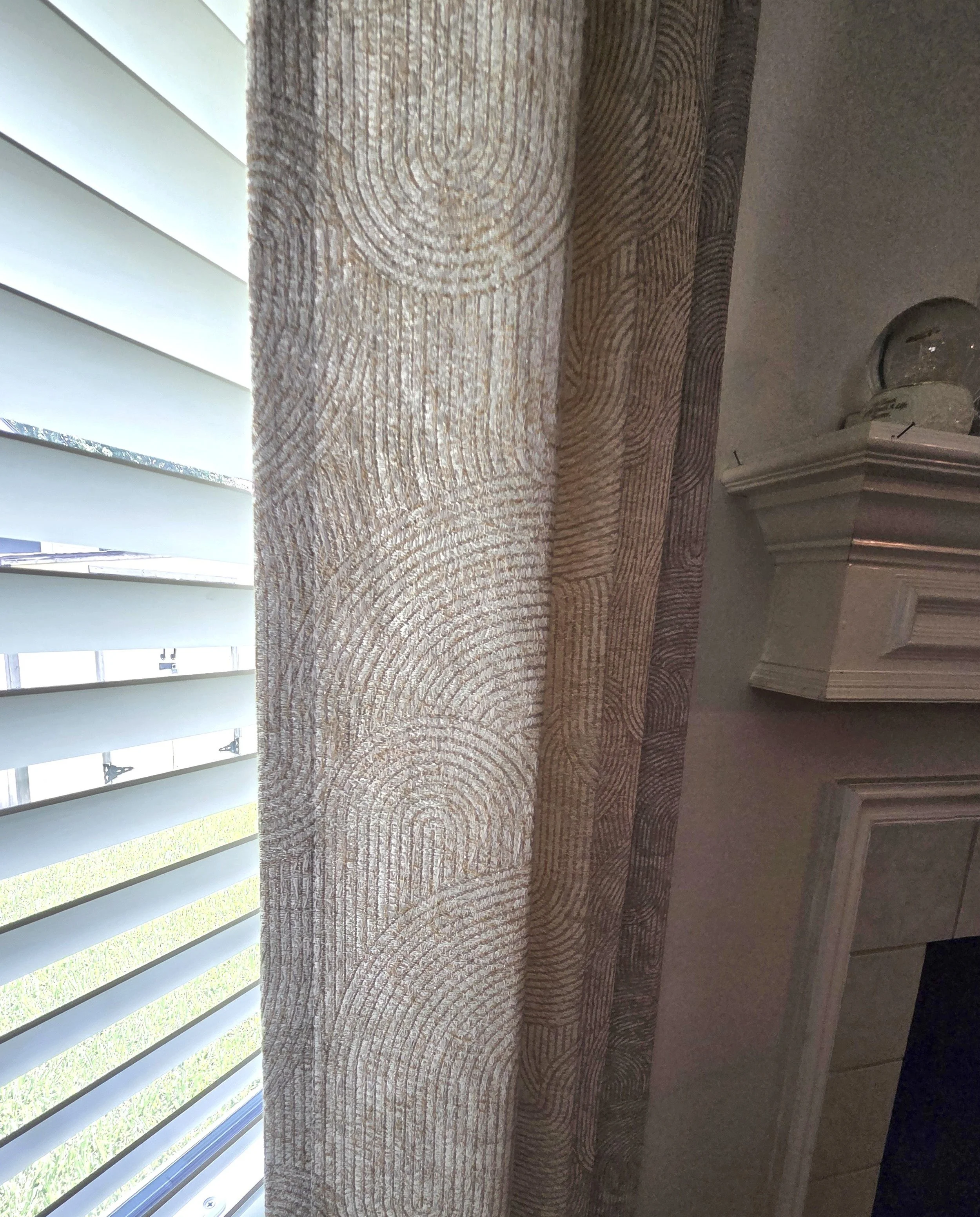 Photo of a window with white blinds and a wooden table or countertop underneath. Houston tx