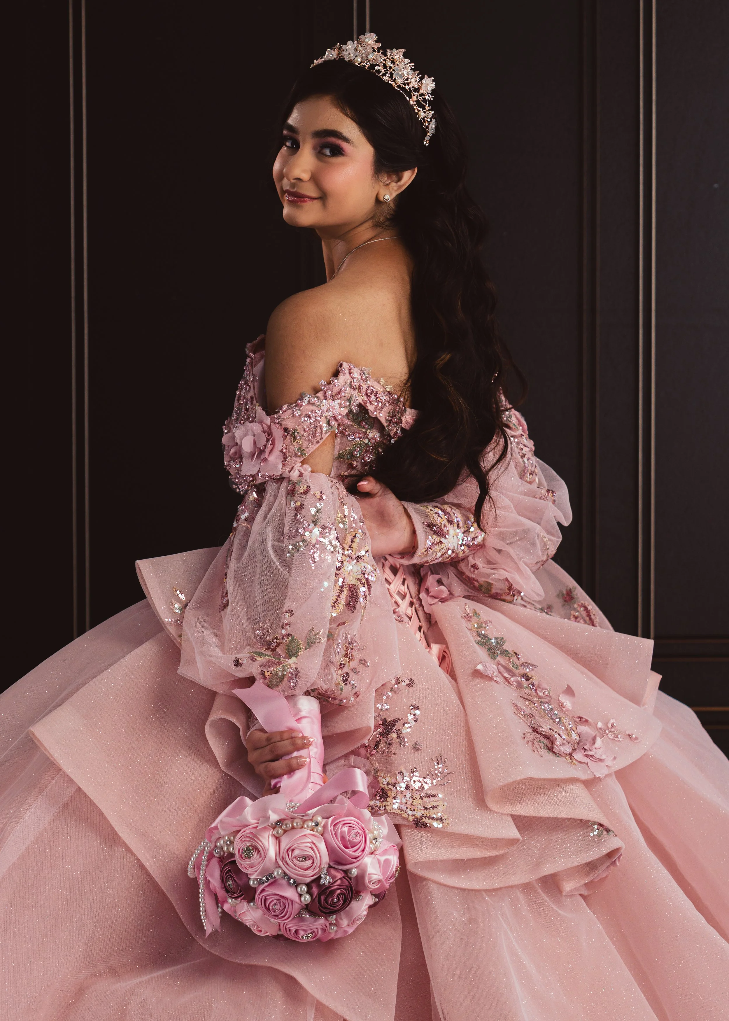 Beautiful formal studio portrait of a young woman in a pink gown and tiara looking over her shoulder, shot at CreativeJuices Studio.