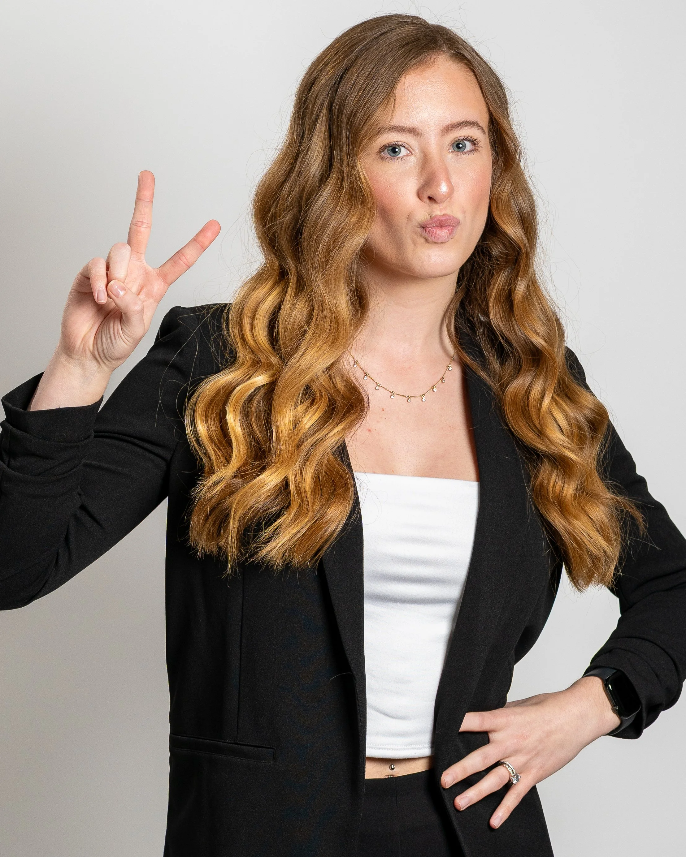 Fun lifestyle headshot of a woman making a peace sign on a clean white seamless backdrop inside our Central Coast photography studio.