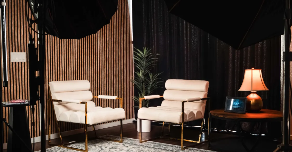 Modern photo studio lounge setup with accent armchair, wood slat backdrop wall, and softbox lighting grid at Creative Juices Studio