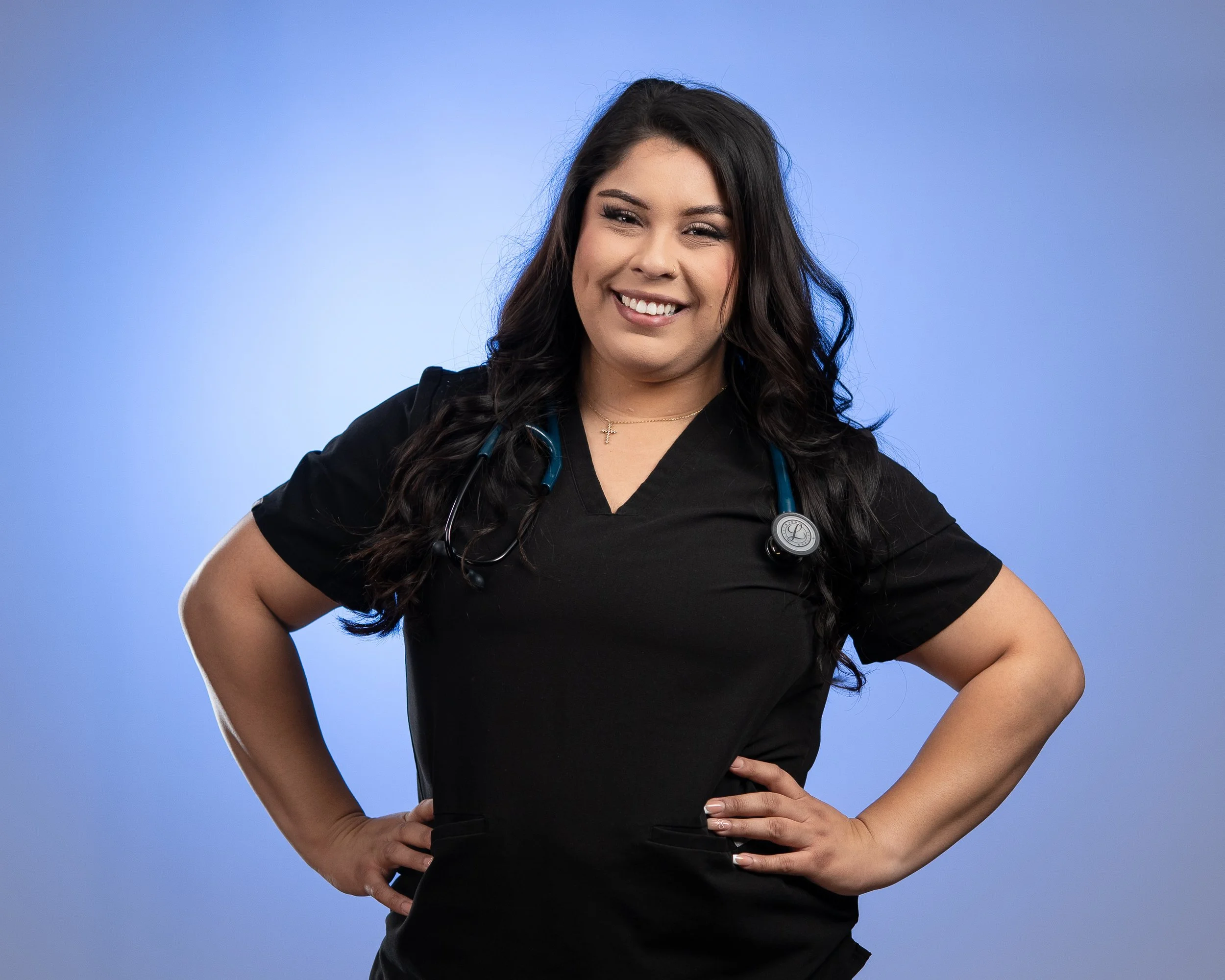Professional headshot of a smiling female healthcare professional in black scrubs with a stethoscope, shot by Sunset Media