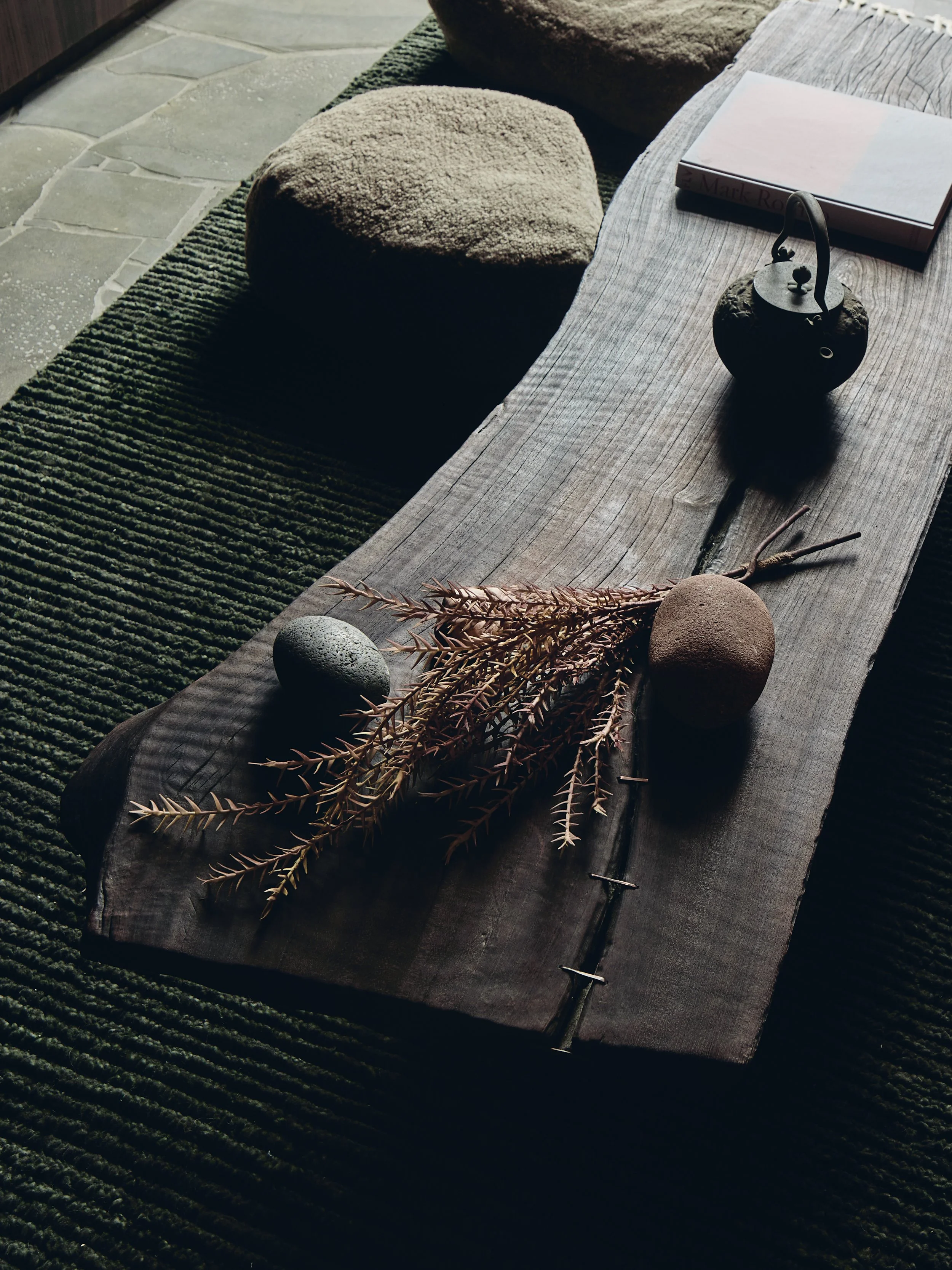 Dried flowers and textured rocks on a smoked timber table
