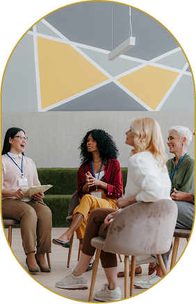 Group of five diverse women sitting and talking in a modern lobby or lounge area.