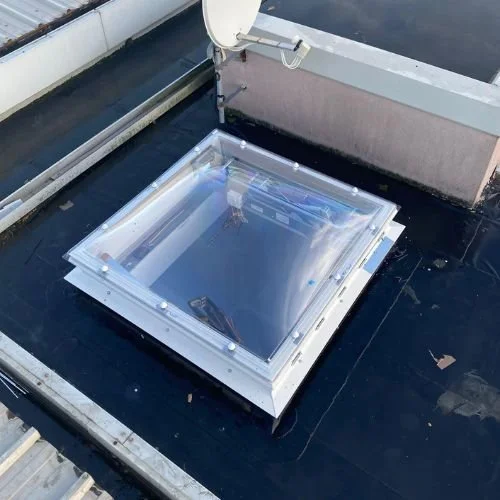 A rooftop skylight with a metal frame and clear glass window.