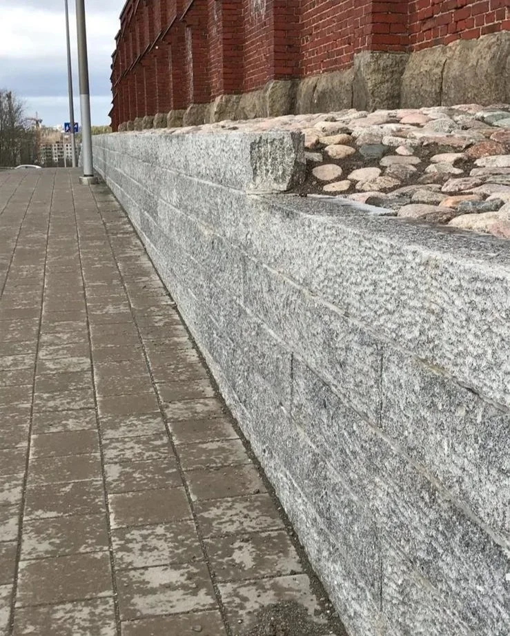 Kuvassa on katu, jossa on tiilinen ja kiviainesmuotoiltu alusta ja kiveyksestä rakennuksen seinämä, joka on valmistettu kivestä ja tiilestä.