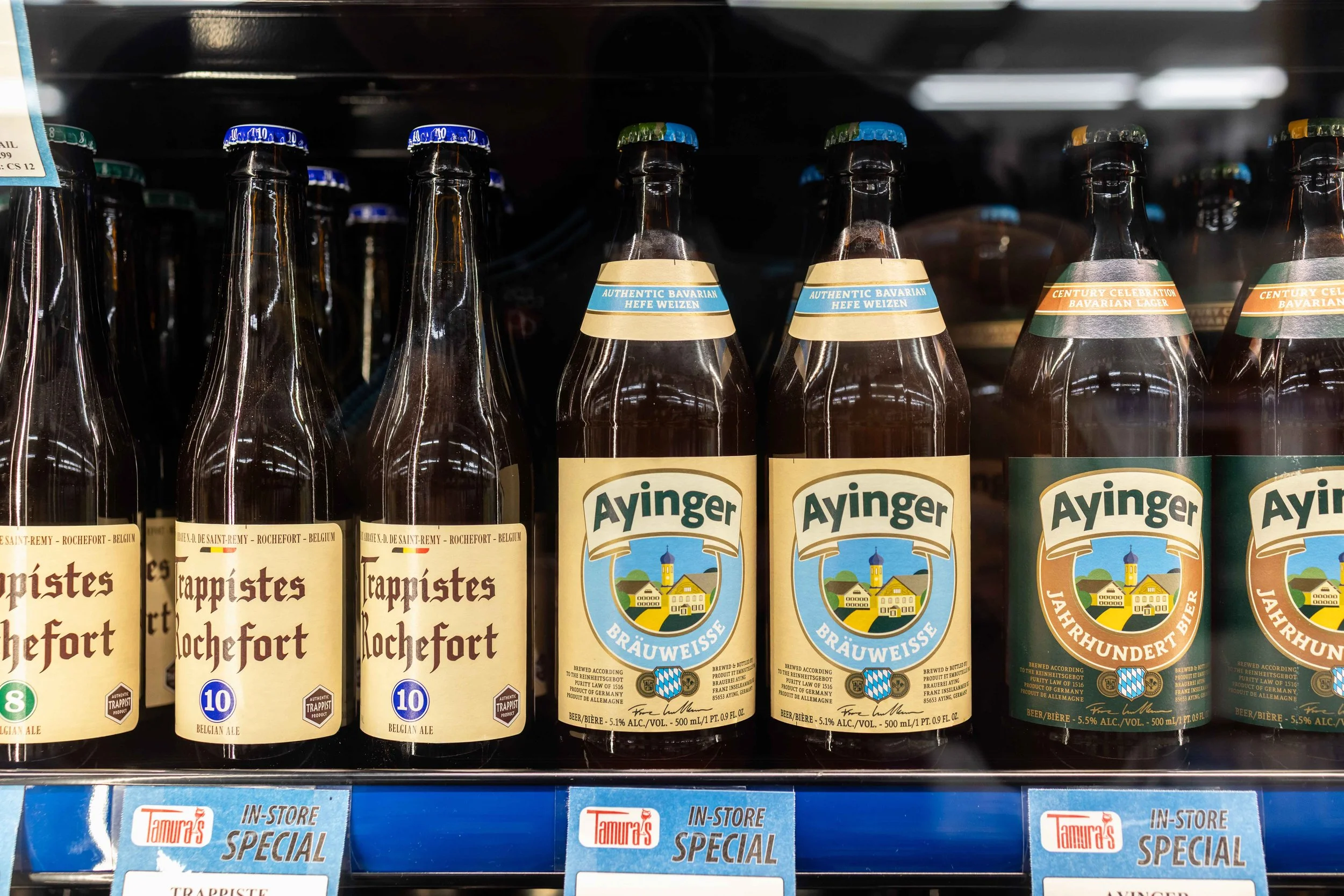 Shelf with bottles of Belgian and Bavarian beer, including Trappistes Rochefort and Ayinger brands.