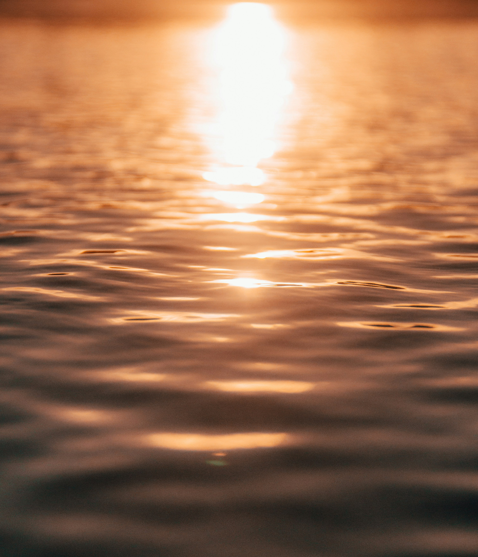 Sunset reflecting on calm water with gentle ripples.