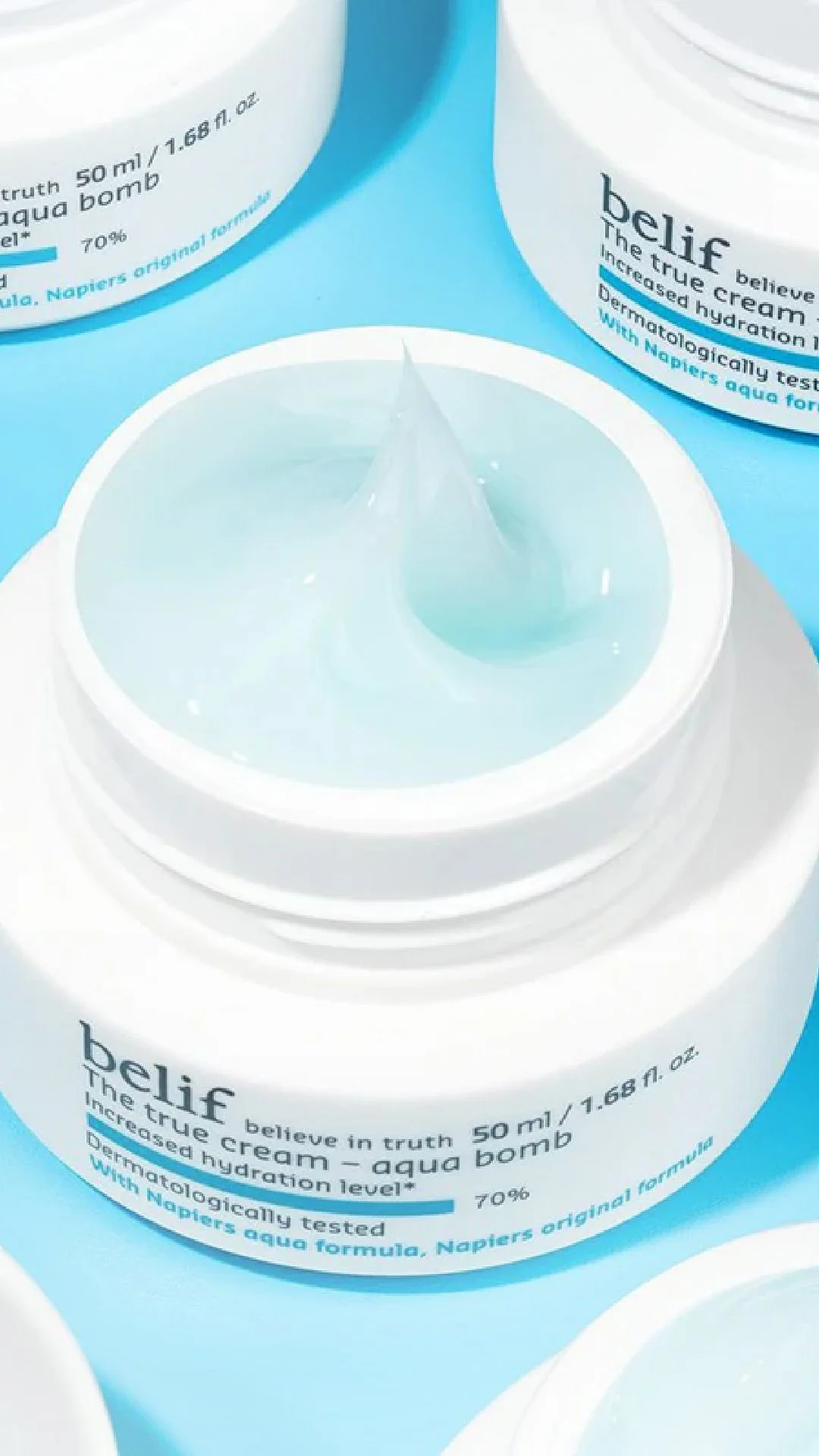 A hand holding a small green bottle of skincare serum with a dropper cap.