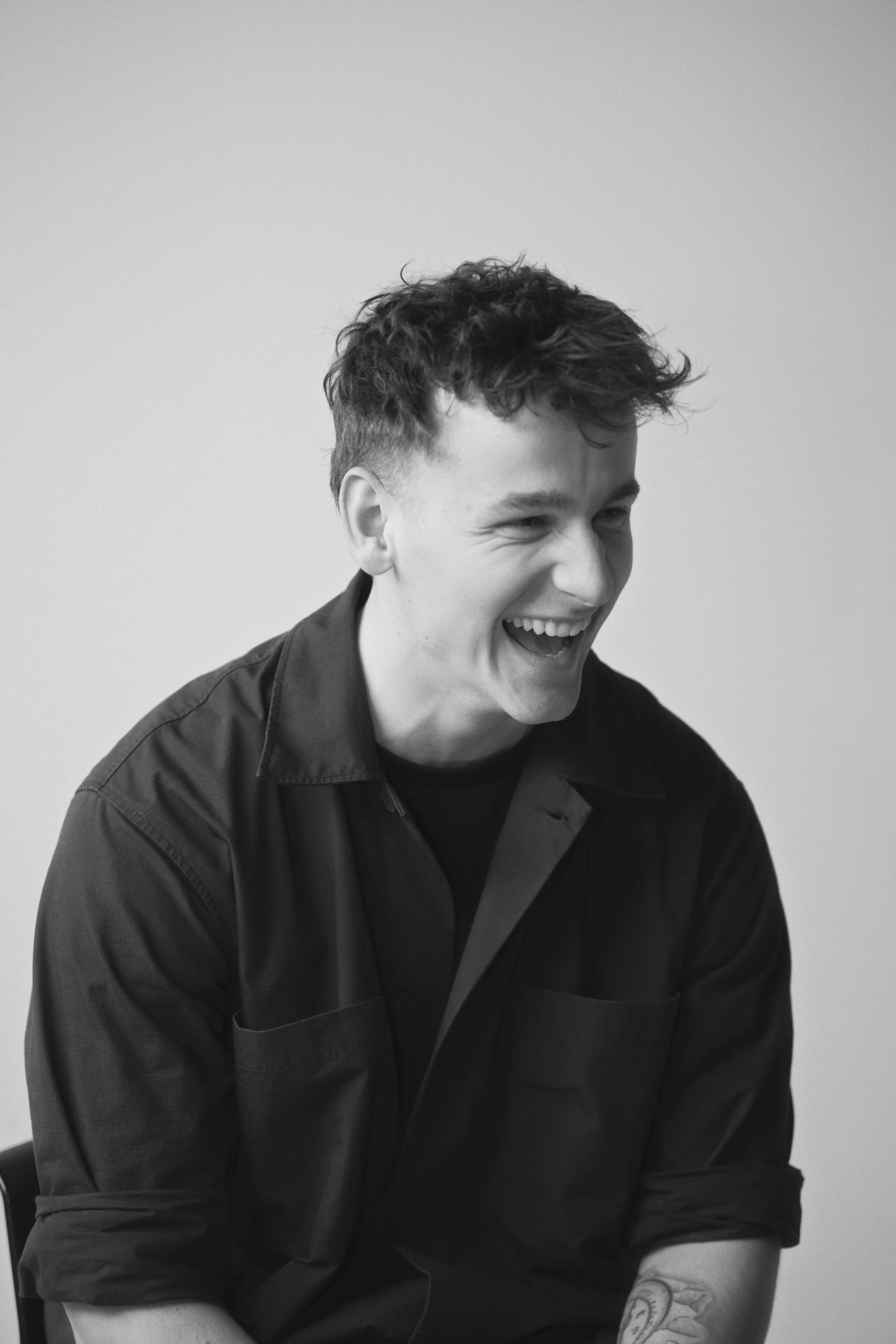 Erhversportræt af ung mand der ler - I sort hvid med grå baggrund