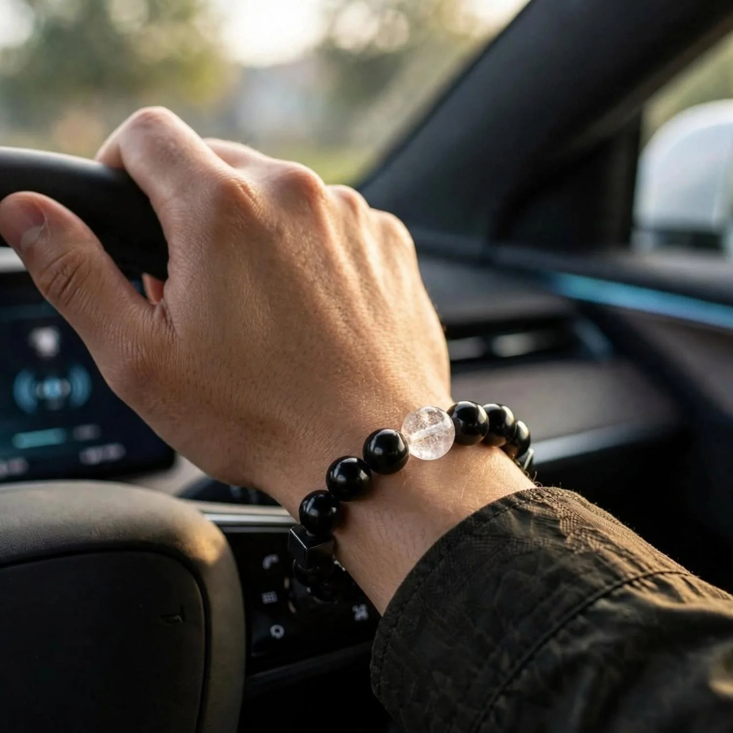 Armband aus Schungit, Hämatit und Turmalin mit Bergkristall am Handgelenk eines Fahrers am Lenkrad