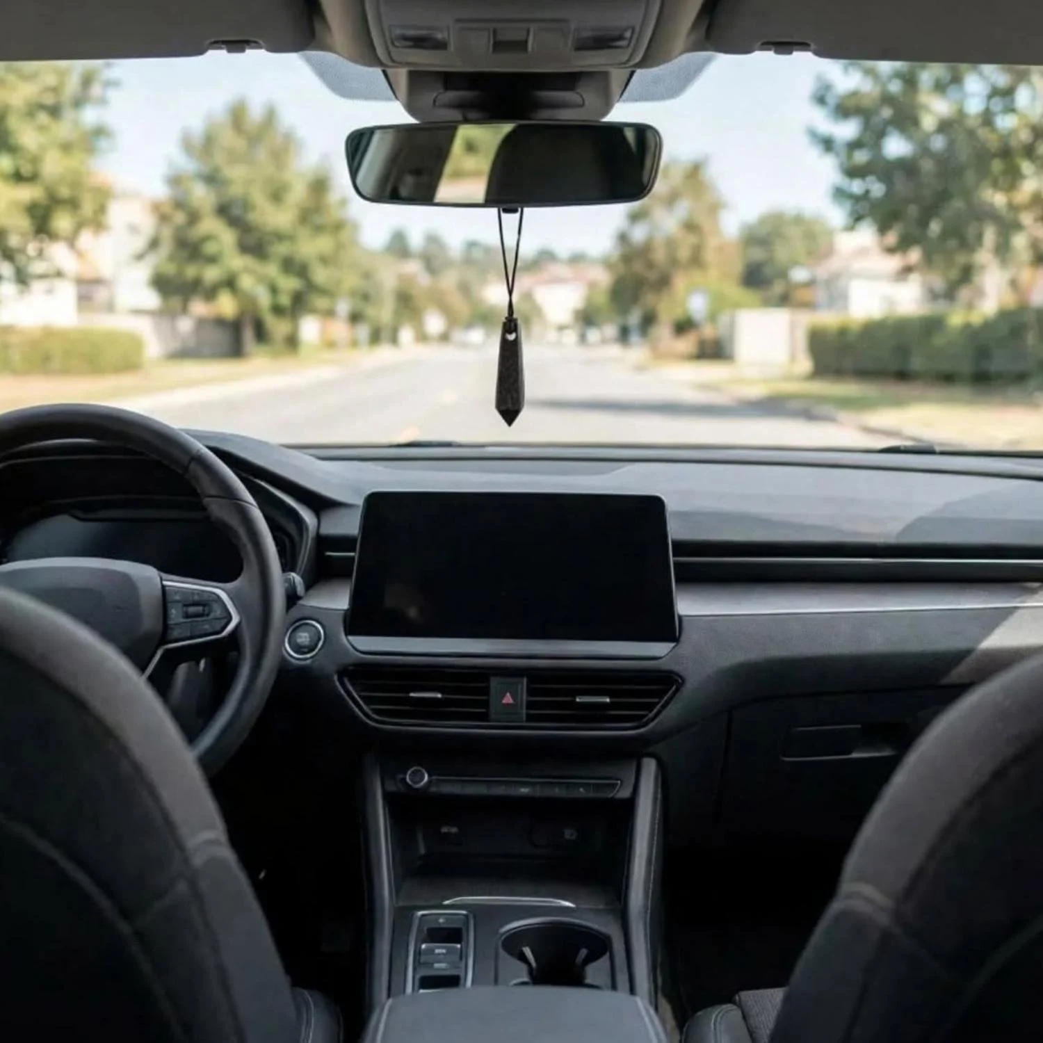 Schungit-Spitzenanhänger am Rückspiegel, dezent im Innenraum eines E-Autos platziert.