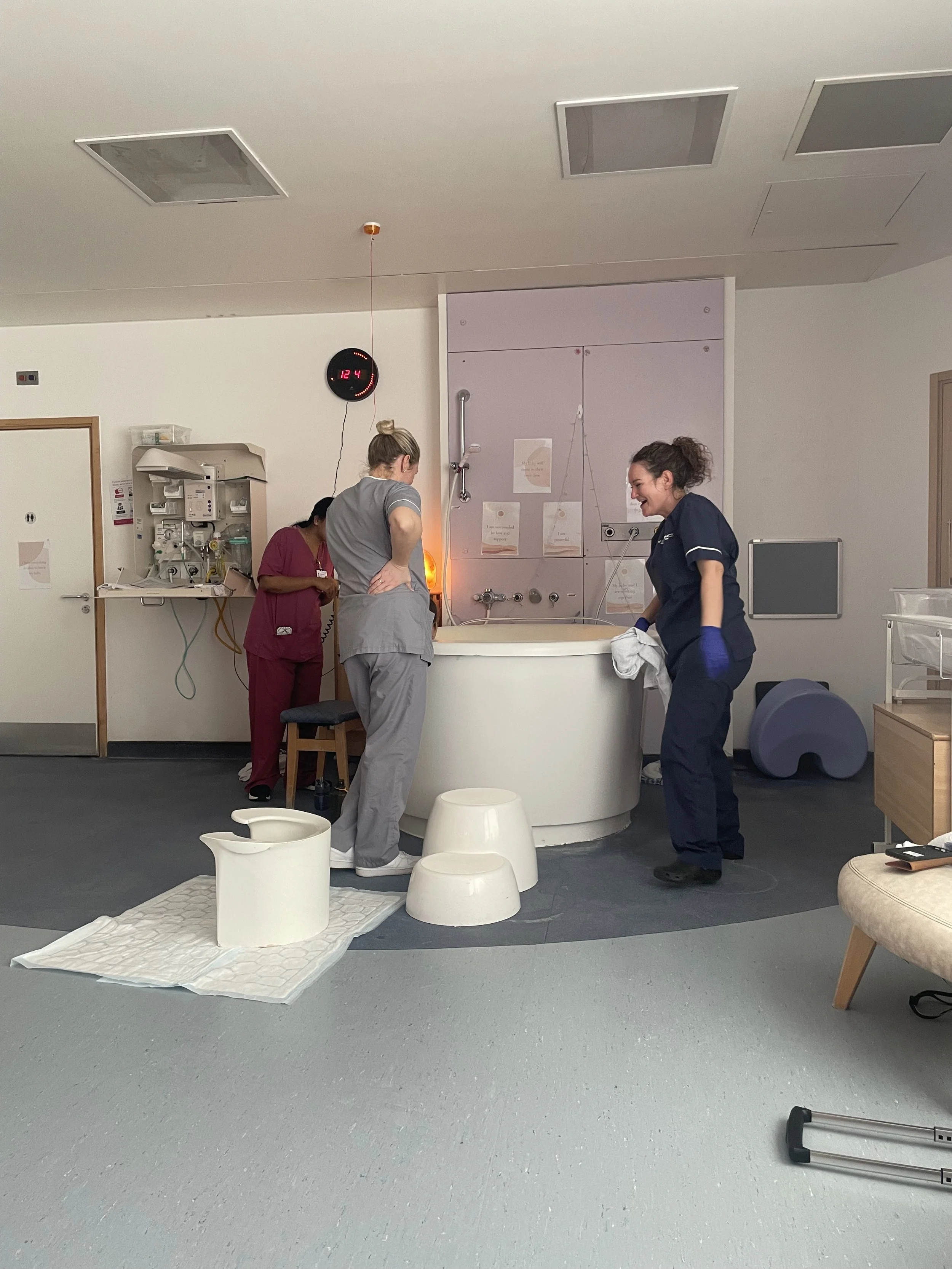 Medical professionals preparing a newborn for a bath in a hospital room.