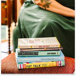Stack of five books on a red upholstered chair.