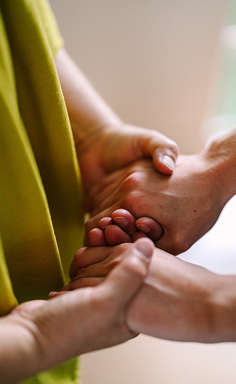 Two people holding hands, showing a gesture of support or comfort.