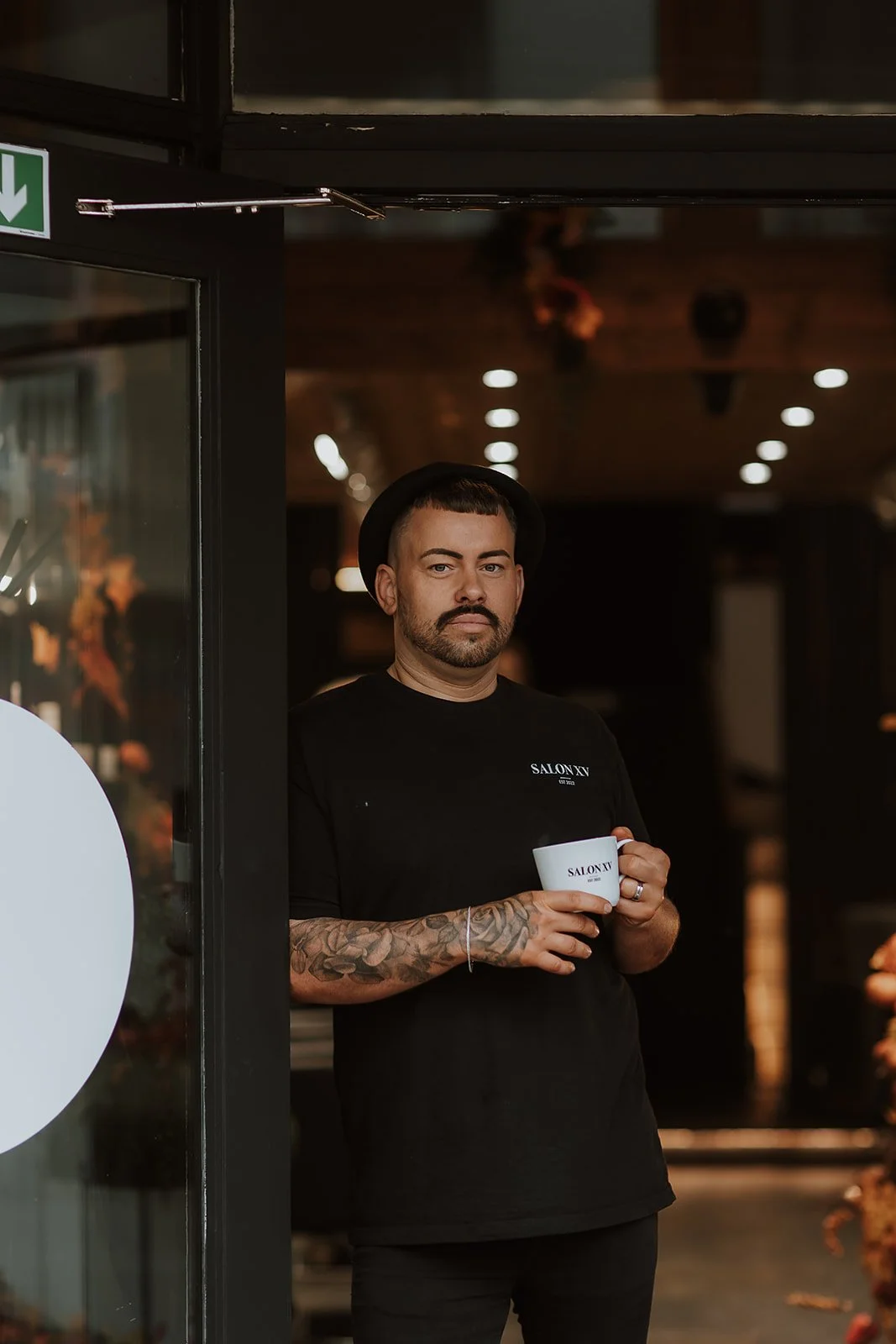 Sam Lewis-Evans, the Co-Founder of Salon XV in Oswestry stood in the doorway of the Salon wearing a black tee shirt