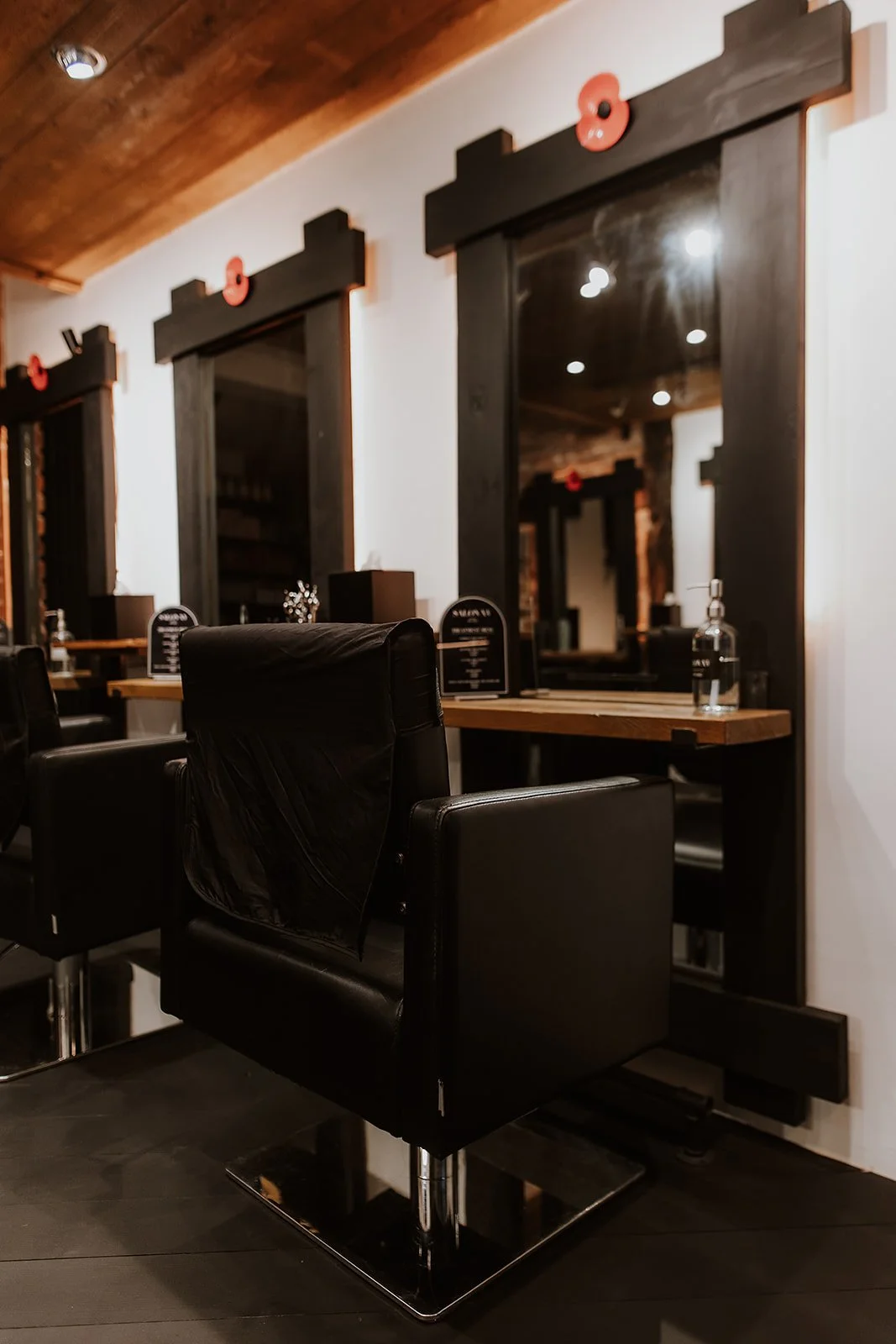 Black salon chairs and mirrors at Salon XV in Oswestry with wooden accents and minimal decor.
