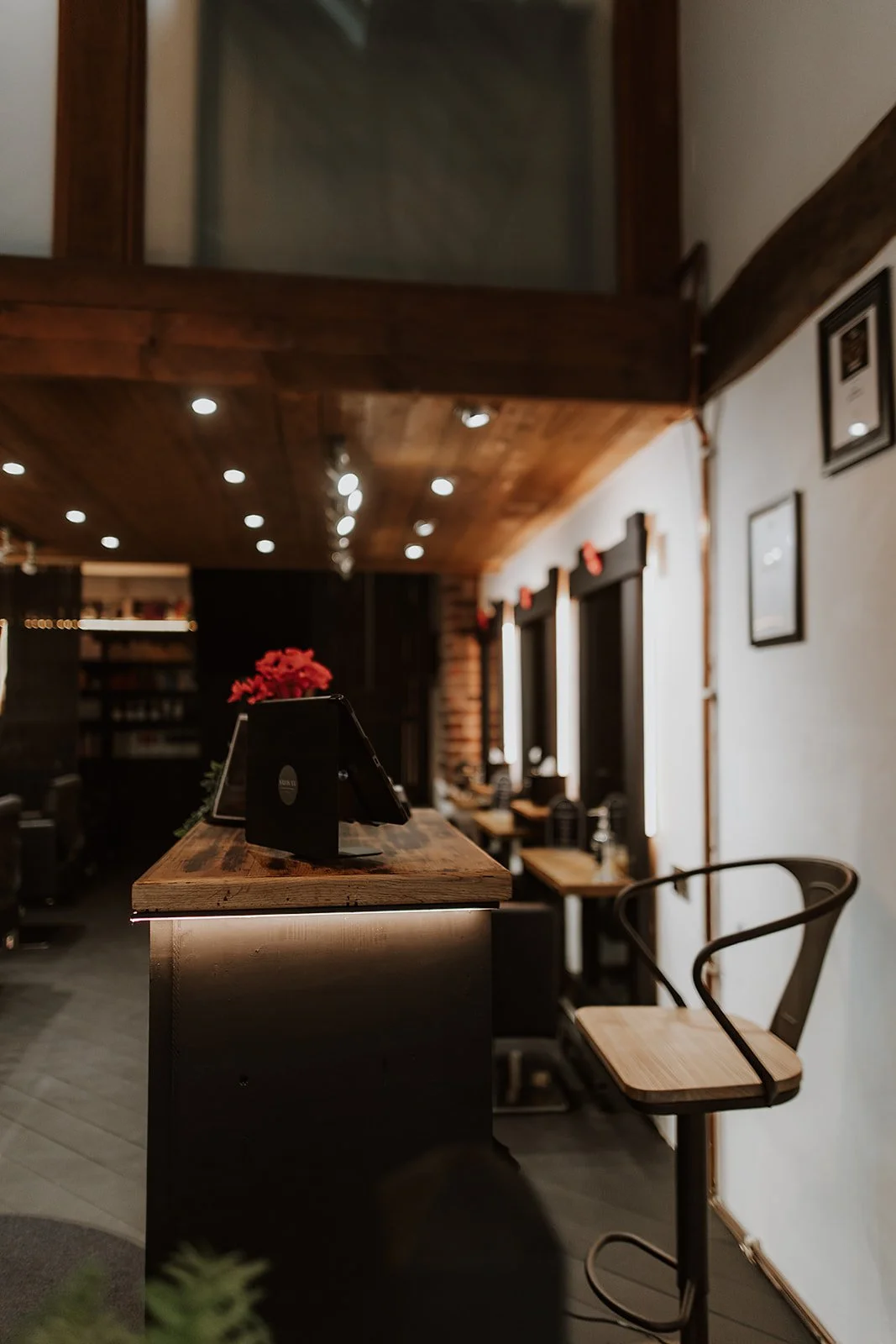 Welcoming interior with wooden ceiling, black chairs at wooden counters, brick accents, and soft lighting at Salon XV on Beatrice Street in Oswestry.
