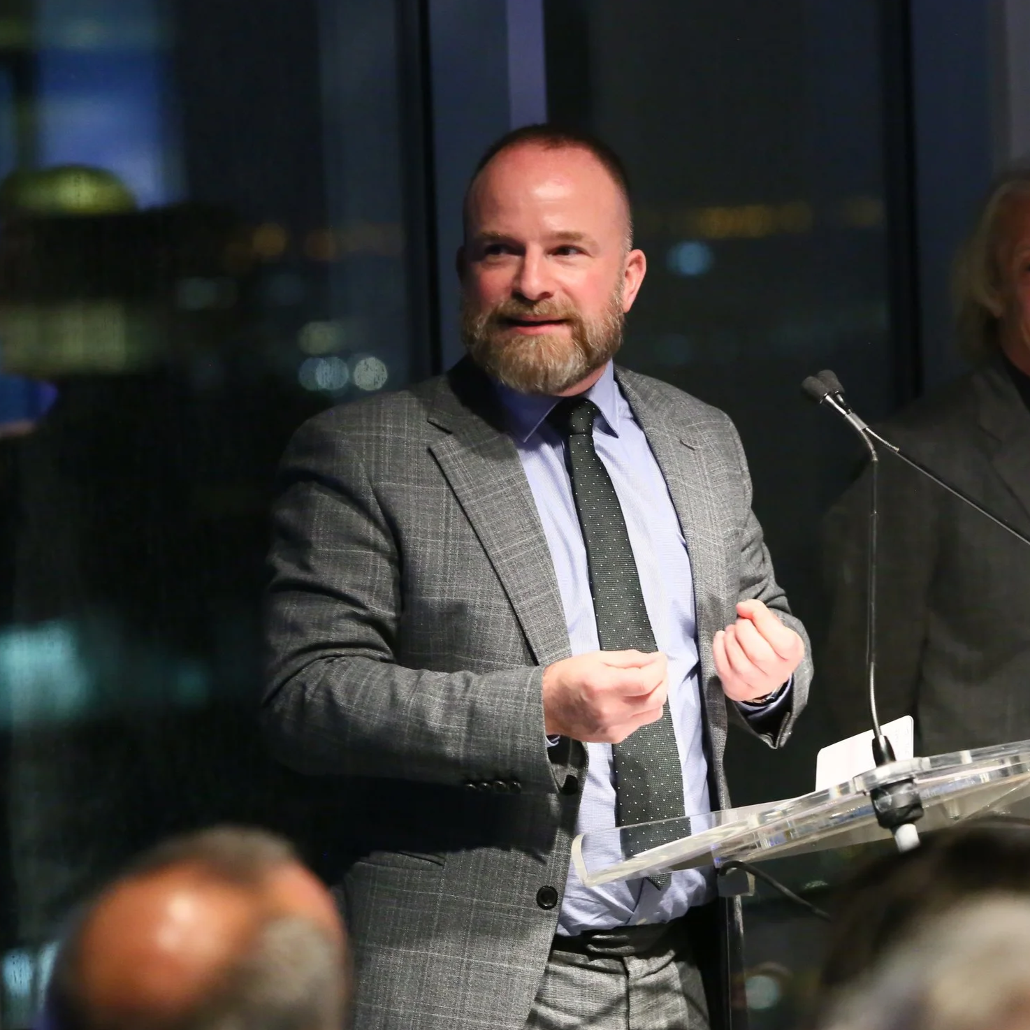 A man wearing a suit standing at a podium giving a speech