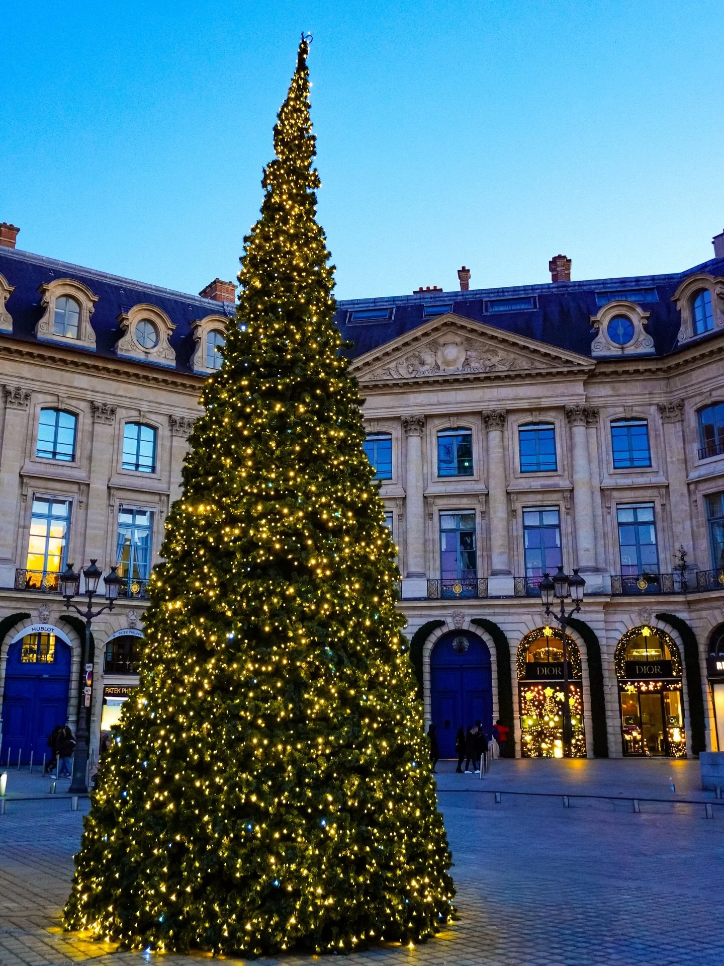 Paris in December feels wrapped in its own quiet glow. Garlands trace the fa&ccedil;ades, windows shimmer with gold and every corner carries a soft promise of celebration. Lights warm the cold air. And for a moment the familiar streets look touched b