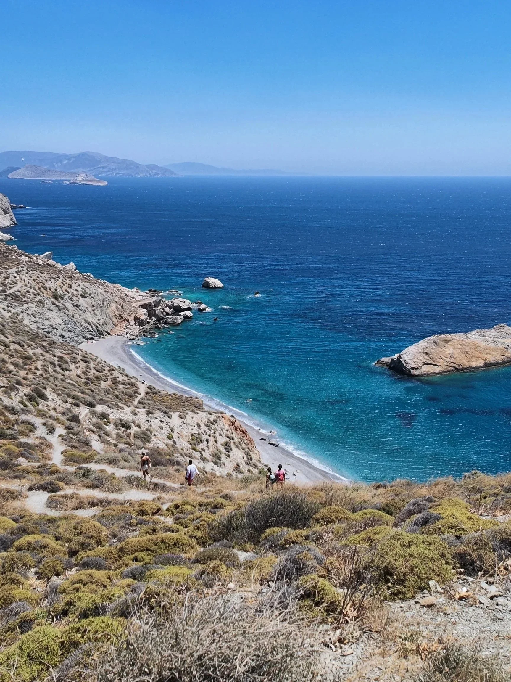 view from the top of Katergo beach in Folegandros with arid vegetation and blue water