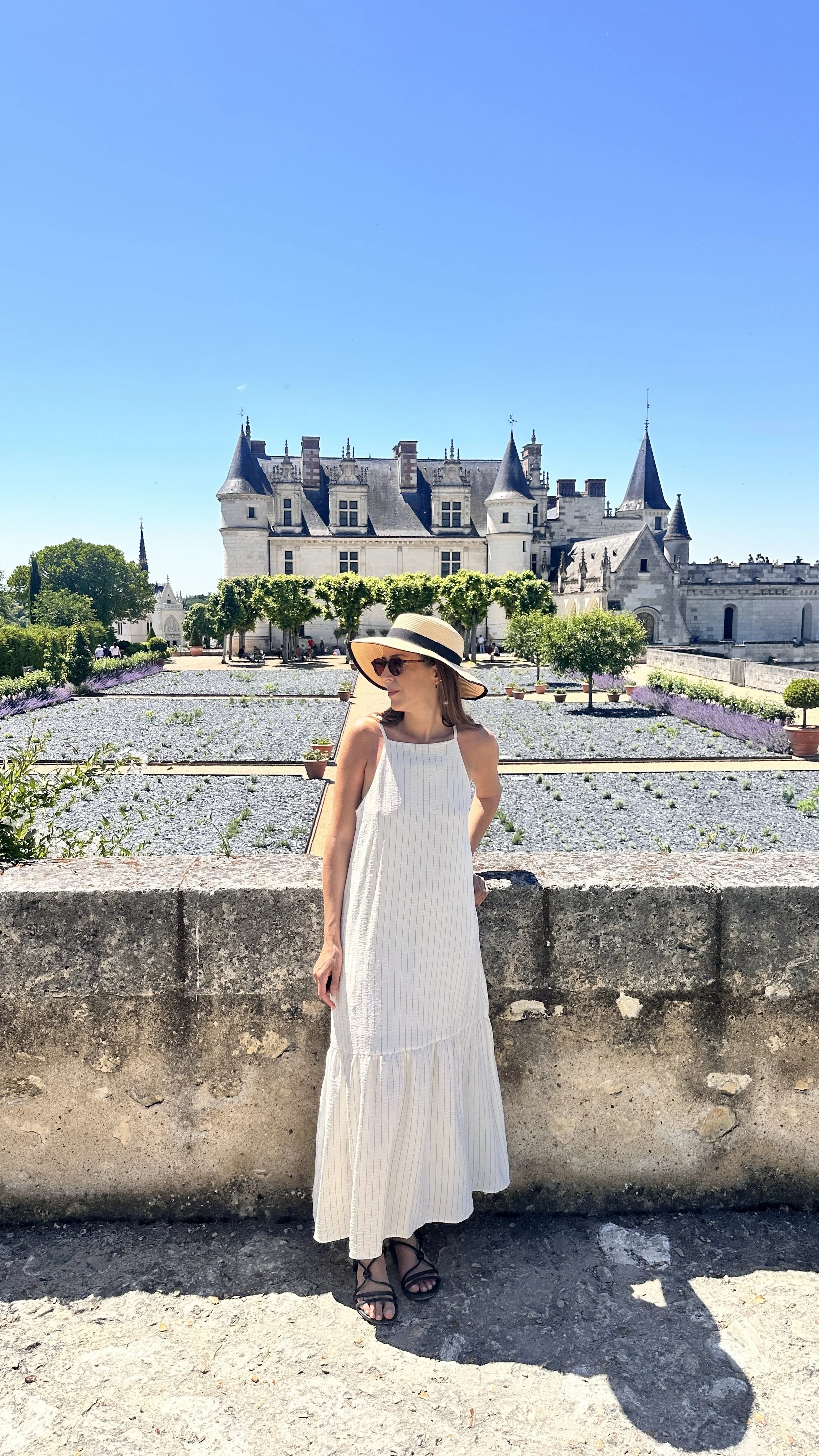 woman with white dress and hat looking the gardens of Chateau d'Amboise France