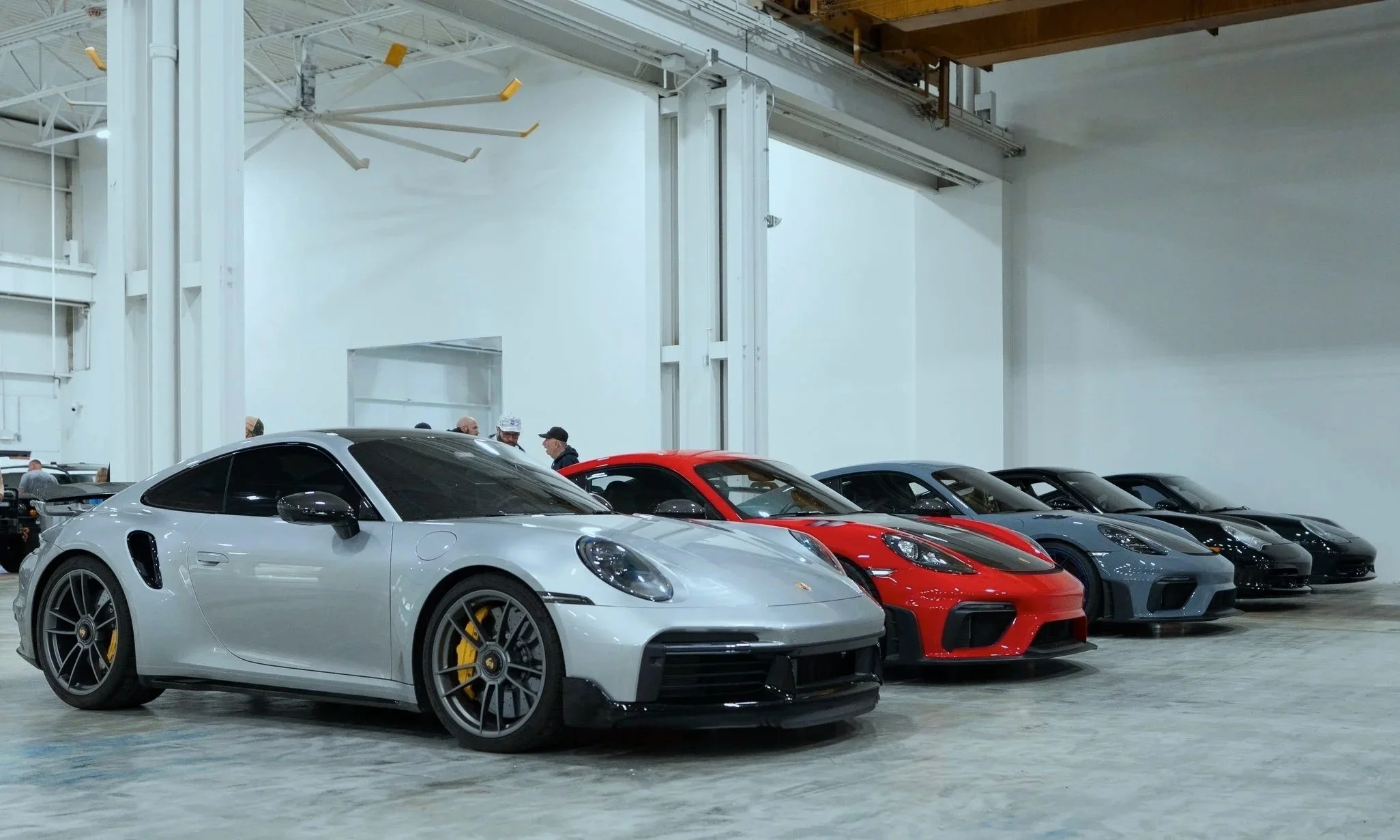 Close-up of a blue Ferrari sports car with a red interior, parked indoors, with other cars in the background.