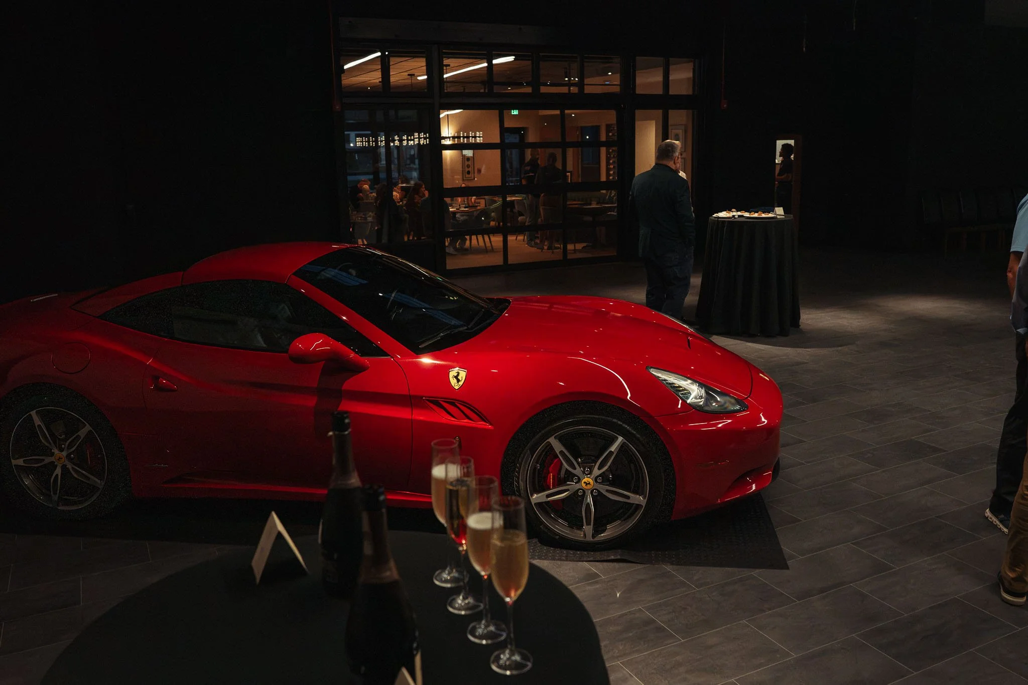 A person in a museum looking at a collection of classic and luxury cars displayed on elevated platforms inside a spacious, well-lit industrial-style building.