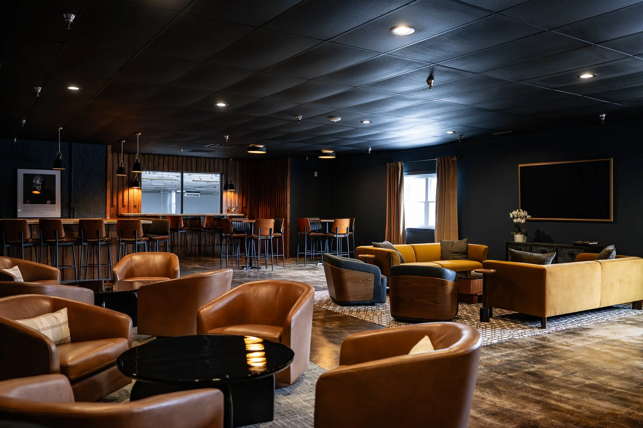 Cozy lounge area with leather armchairs, a small round marble-topped table, a brick wall with a mirror, and a modern linear fireplace.