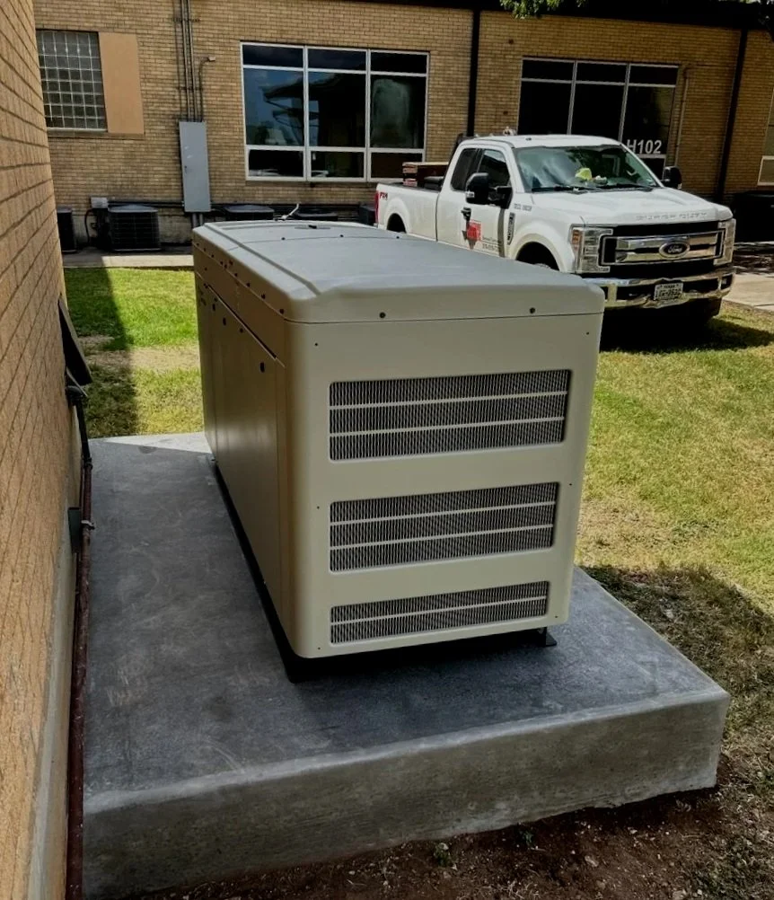 An HVAC condenser outside a brick building on a concrete pad with a pickup truck parked nearby.