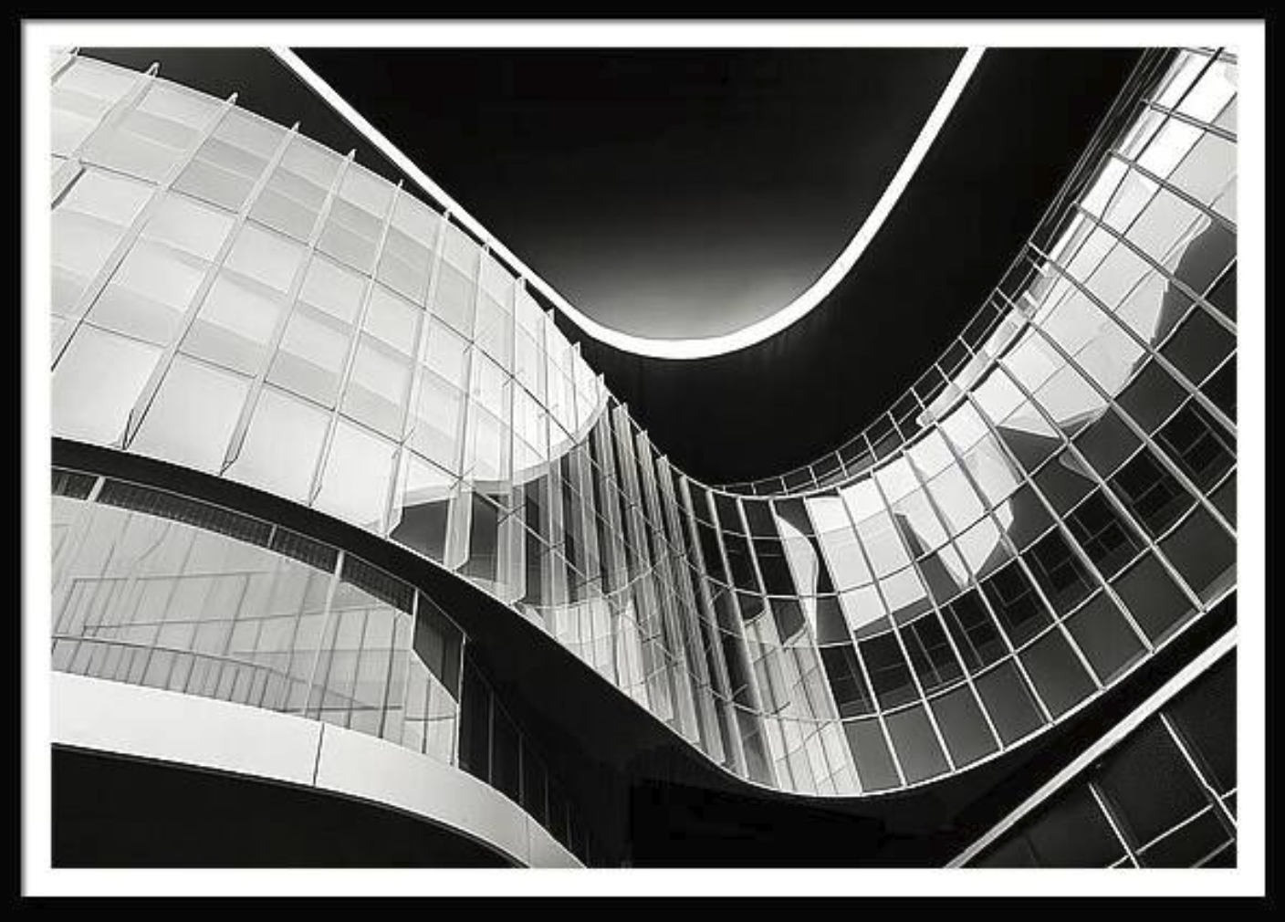 Black and white photograph of a modern building with curved glass facade and illuminated outline, viewed from below.