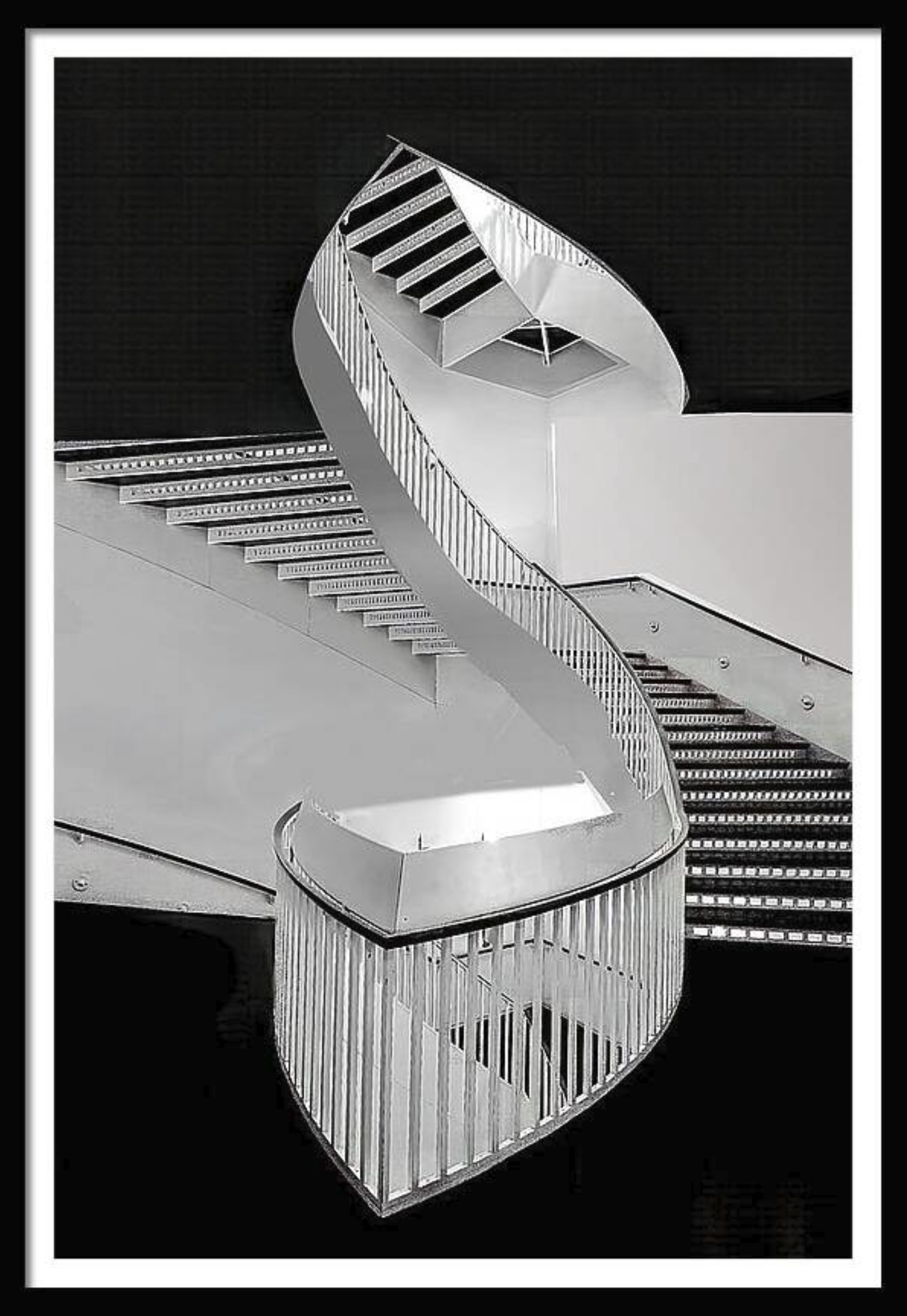 Black and white photo of a spiral staircase with a modern design, featuring curved railings and steps that ascend around a central axis.