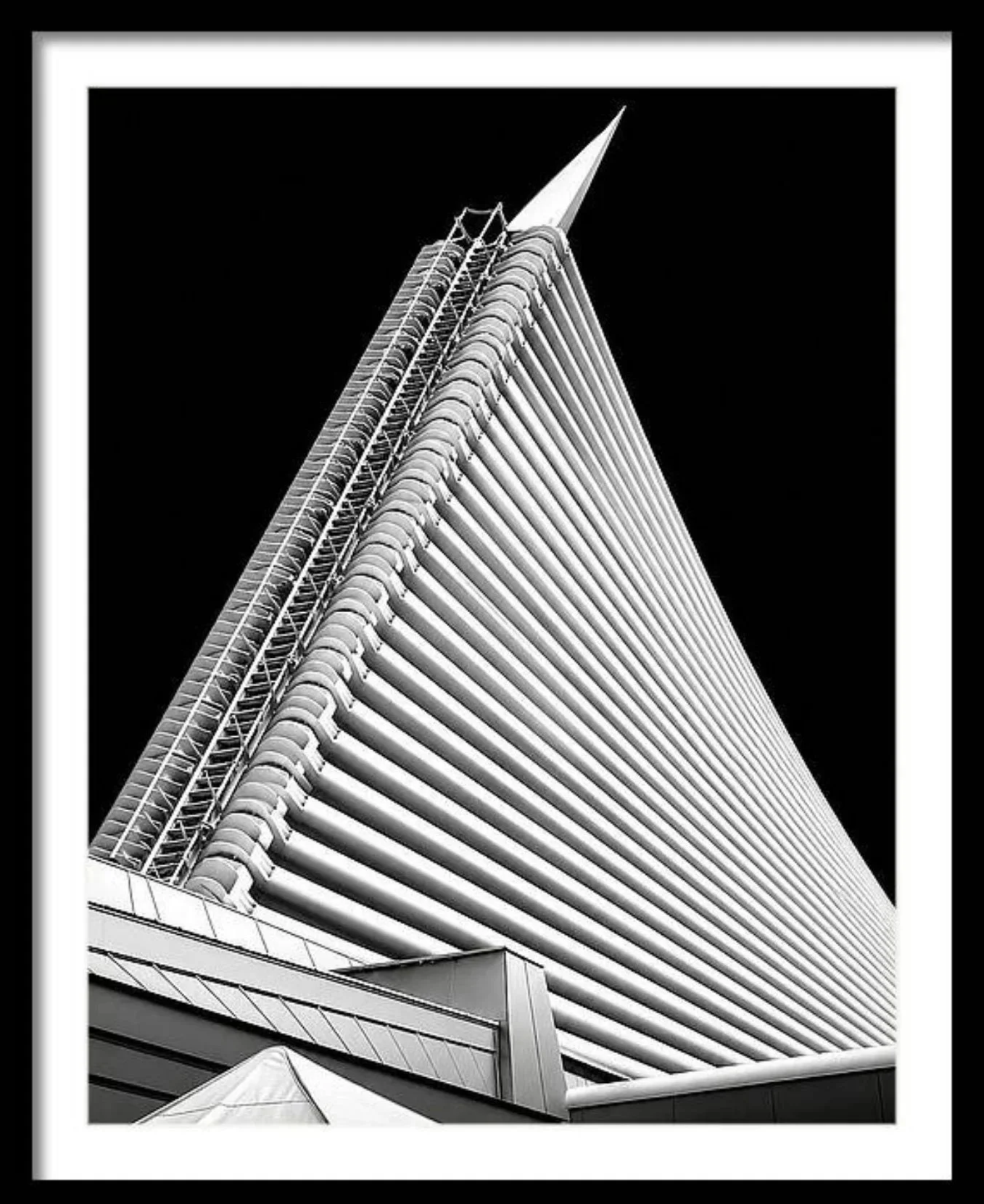 Black and white photograph of a modern building with horizontal lines and a pointed top.
