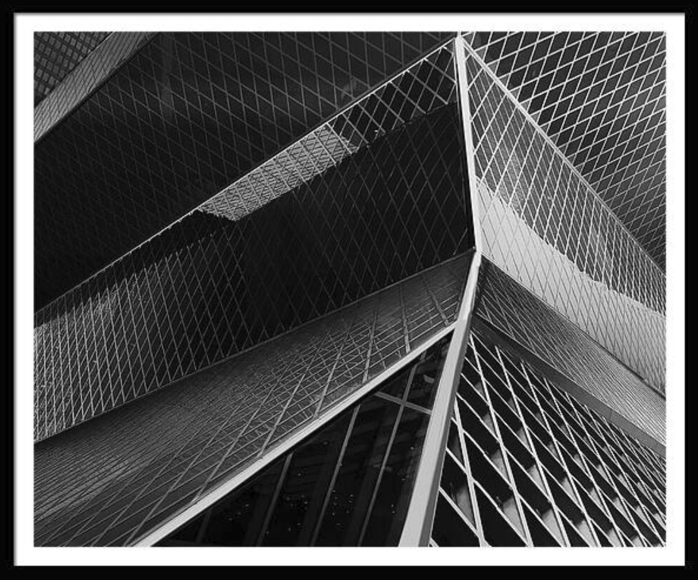 Black and white photo of a modern glass skyscraper, seen from below.