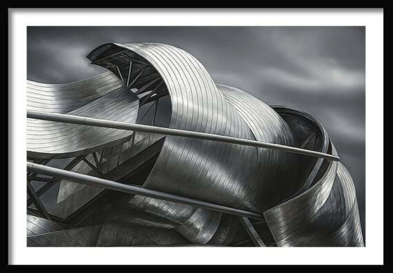 Modern architectural building made of metal with curved and angular surfaces under a cloudy sky.