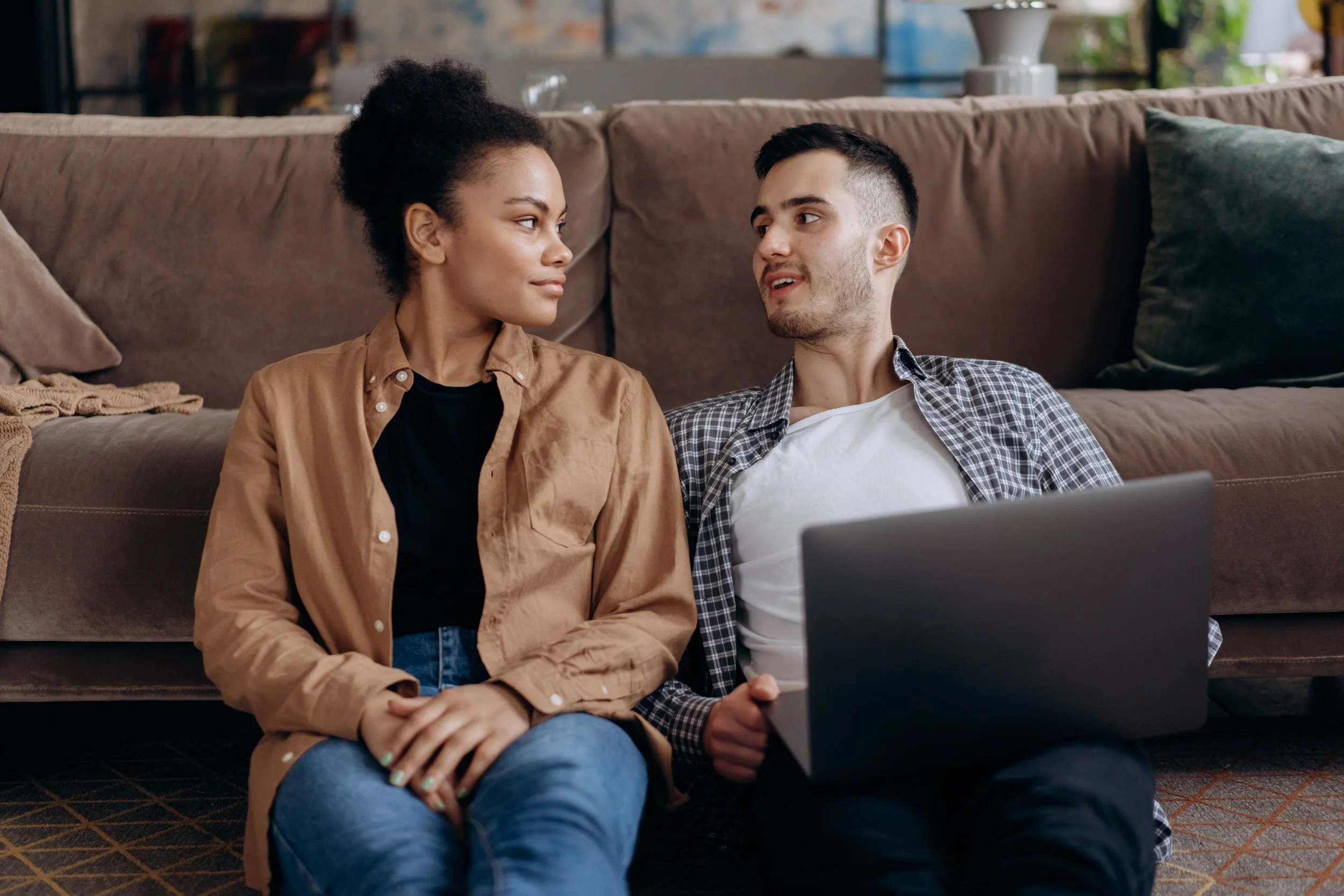 male female couple 20s 30s sitting front of couch having important conversation about family planning TTC having kids
