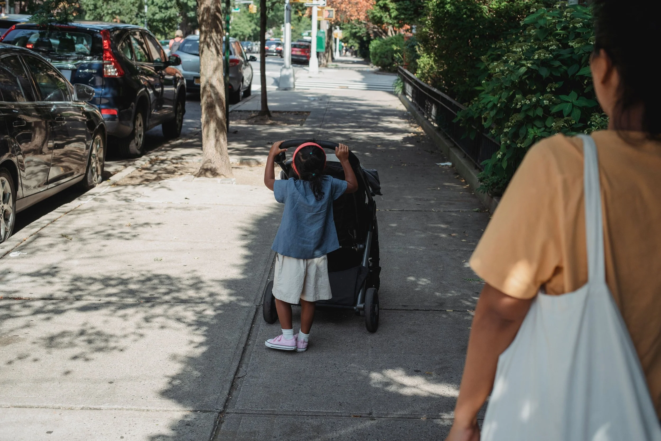 mom and young daughter city sidewalk daughter pushing stroller mom admiring hoboken jersey city