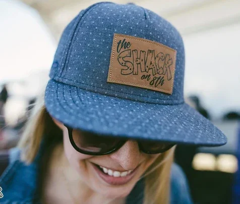 A person wearing a blue cap with a brown patch that says 'the shiners on 81' and black sunglasses, smiling.