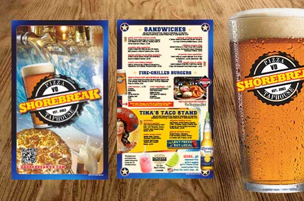 Shorebreak beer coaster, restaurant menu, and a filled glass of beer on a wooden table.