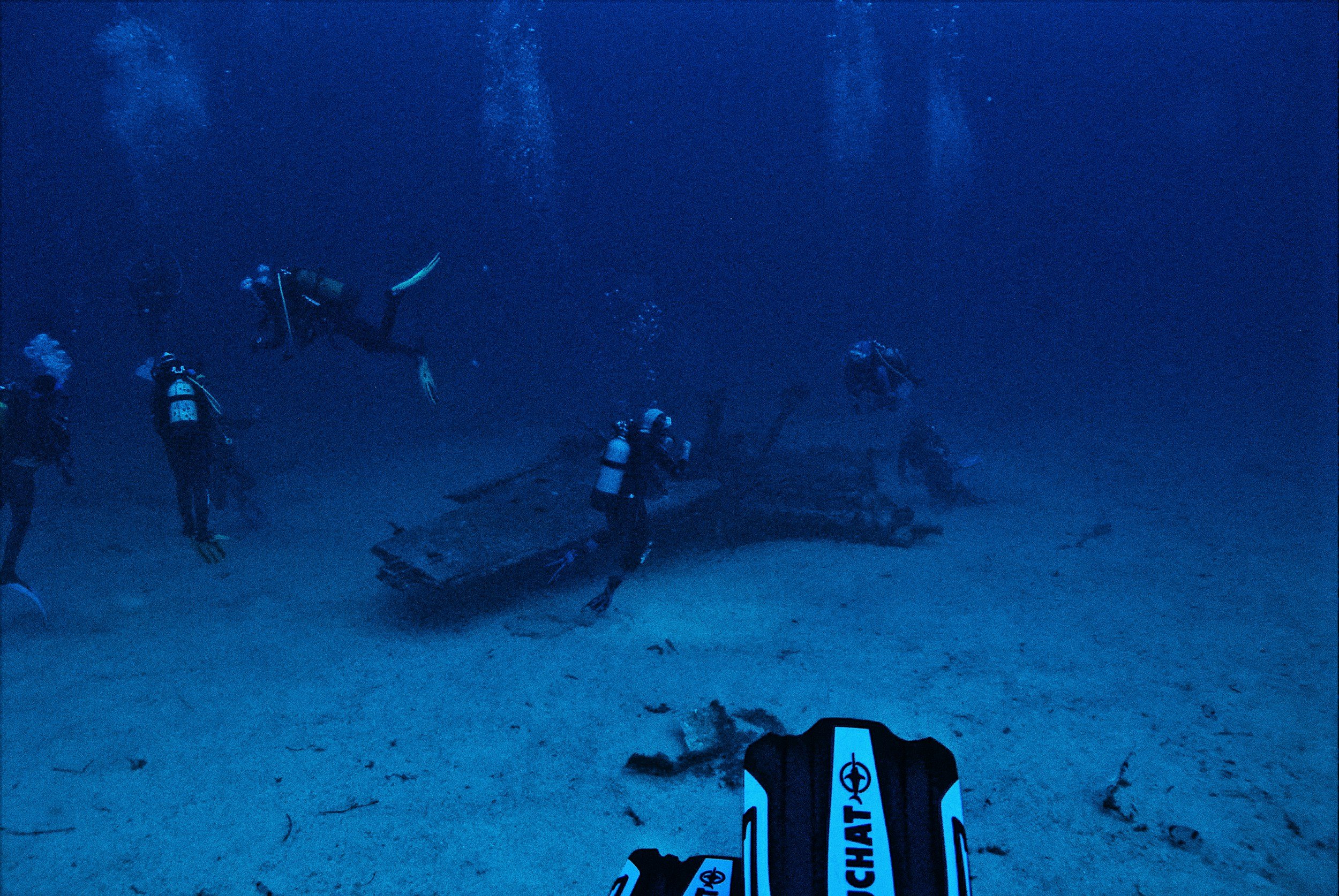 SD911 Scuba divers exploring a sunken shipwreck underwater.